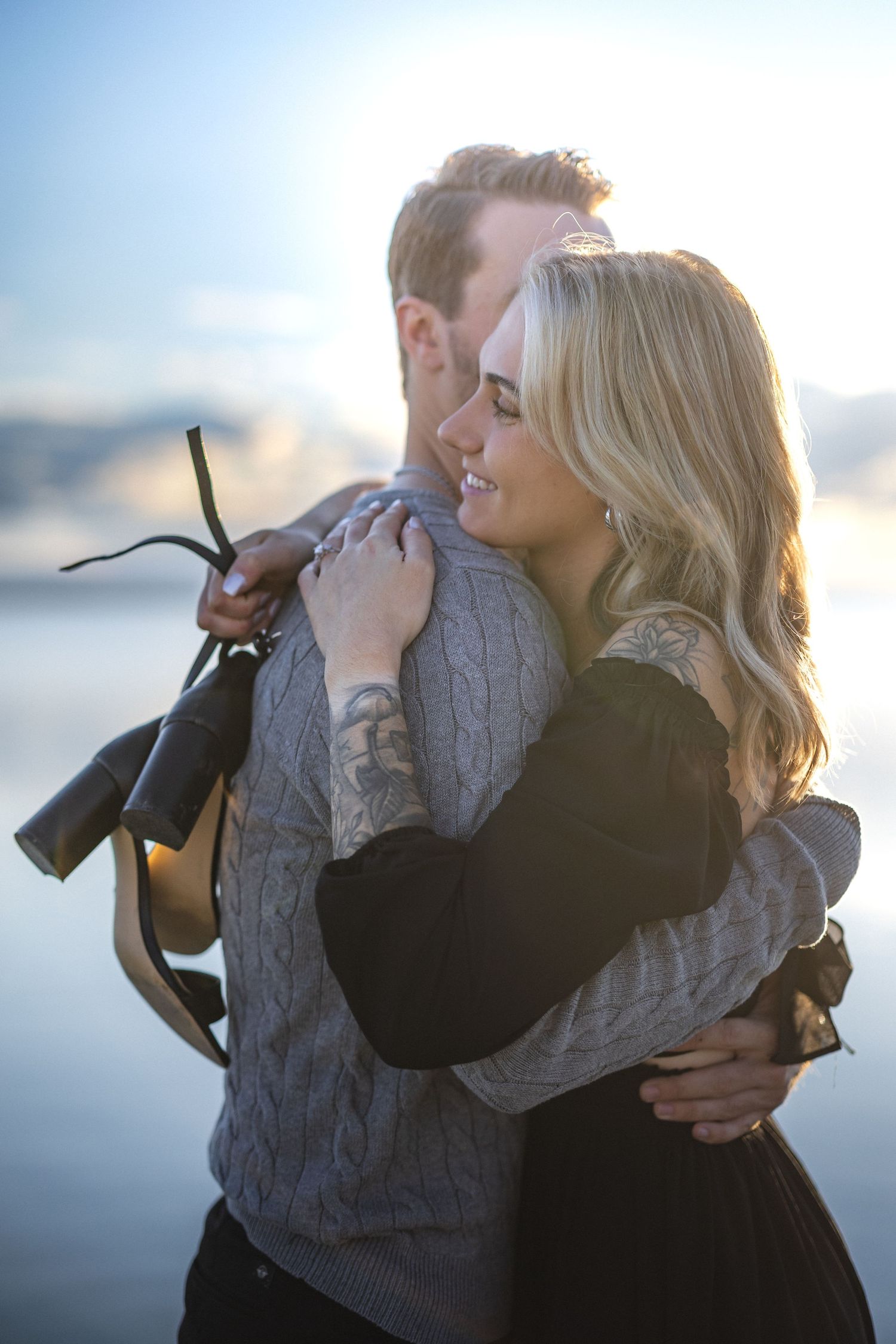 Romantic embrace on a misty waterfront with soft natural lighting.