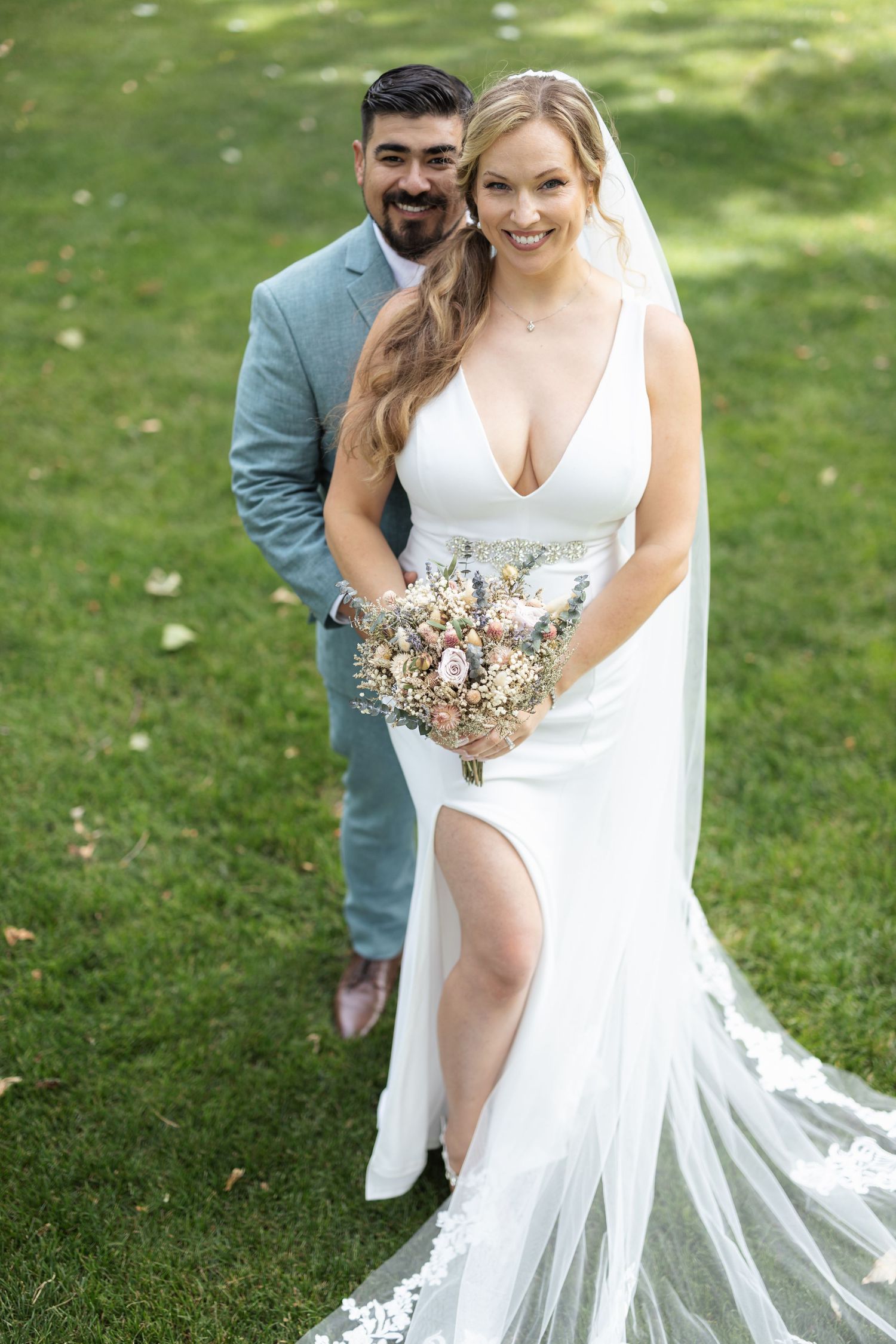 Romantic wedding portrait of couple in white dress and light blue suit with dried flower bouquet.