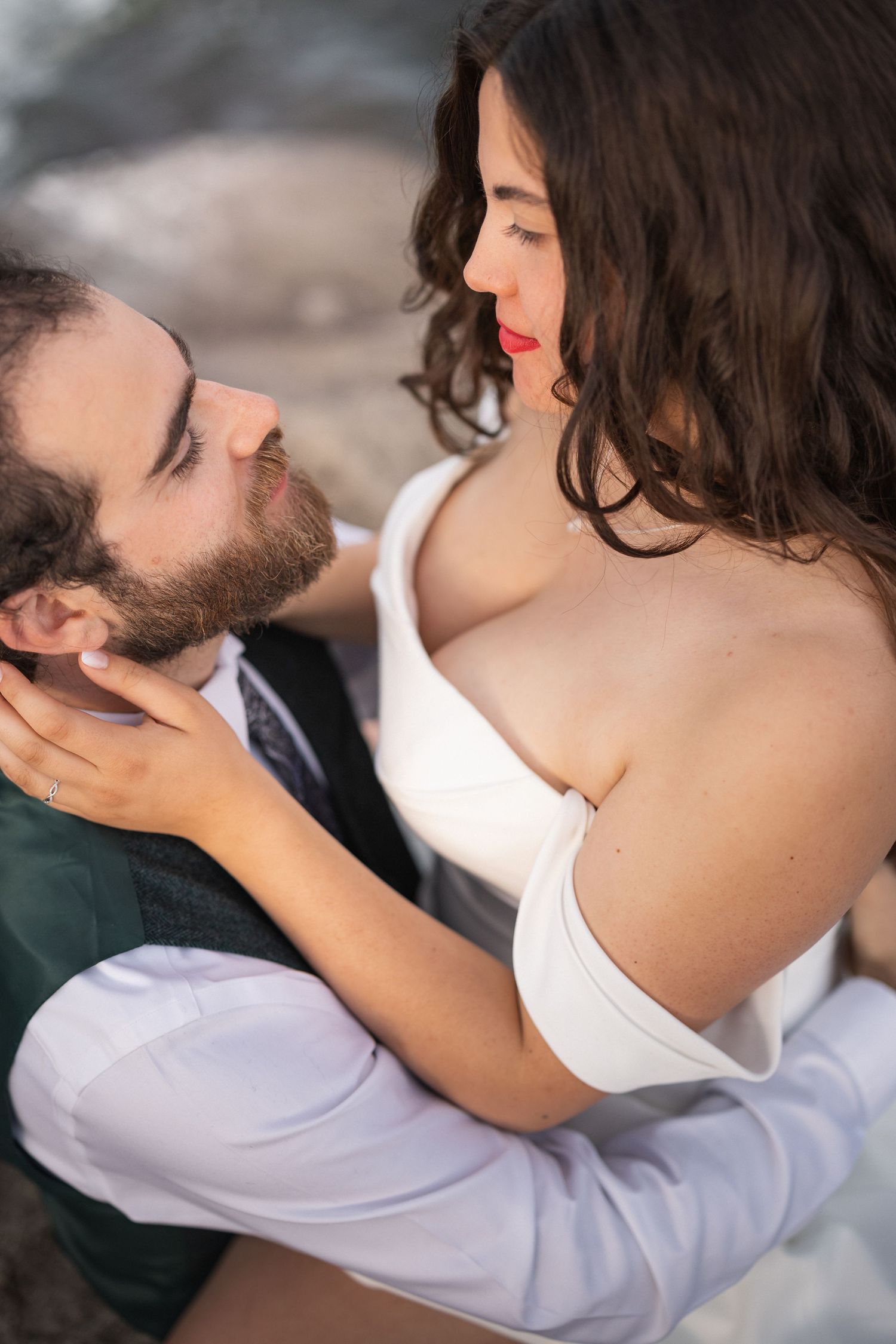 Intimate close-up of couple in wedding attire sharing tender moment outdoors.