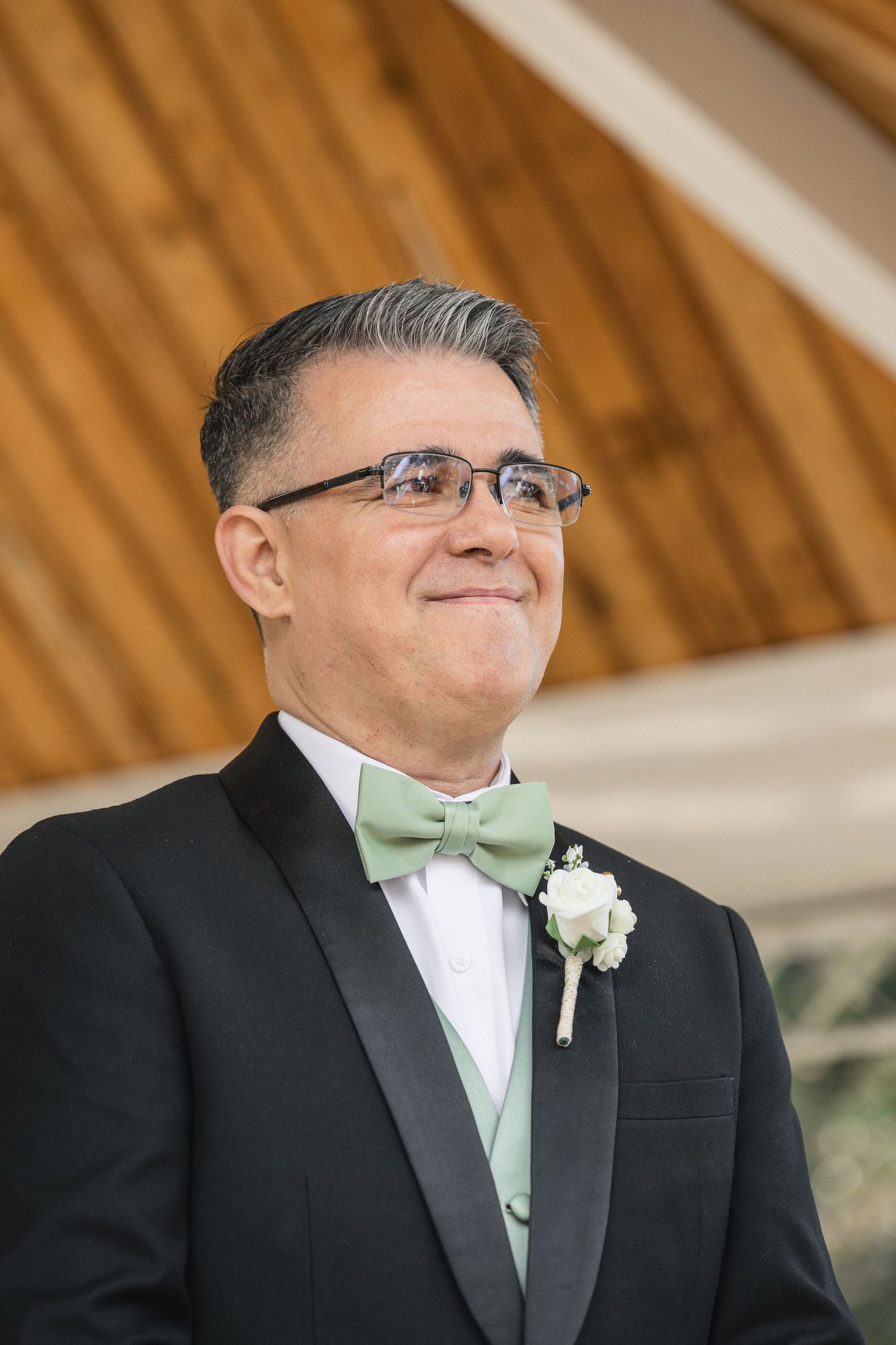 Formal portrait of someone wearing a black tuxedo with mint green bowtie and boutonniere.