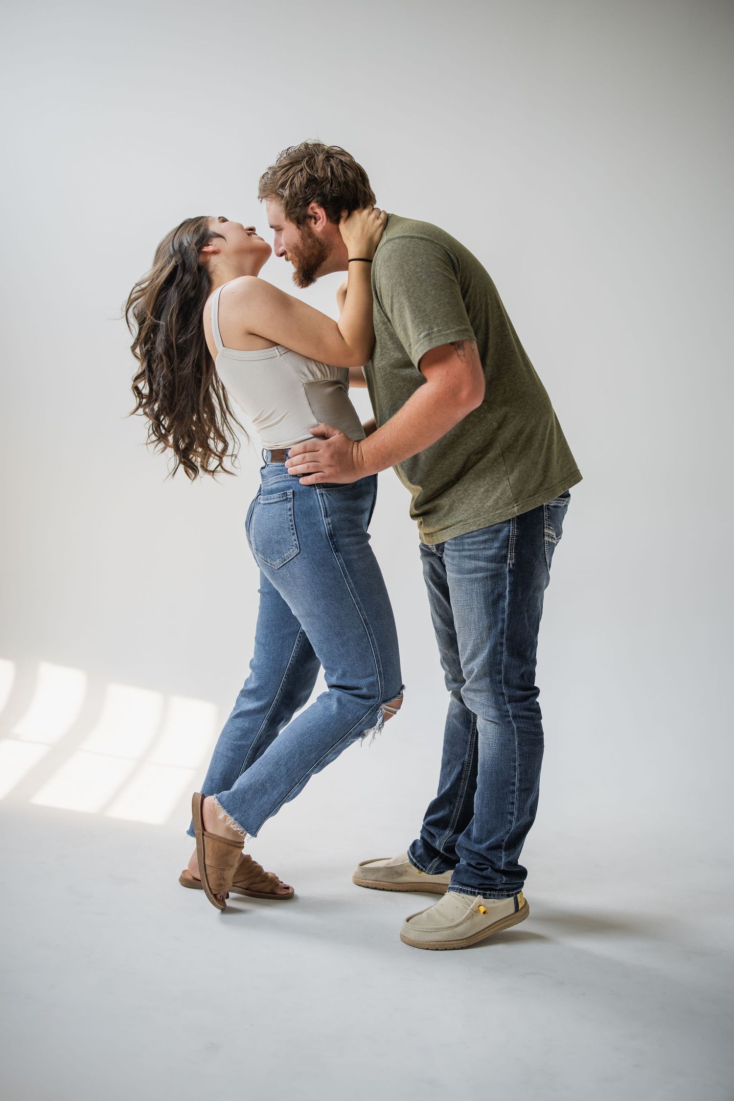 A couple in casual attire dances together on a white studio floor, showing playful dance movements in sequence.