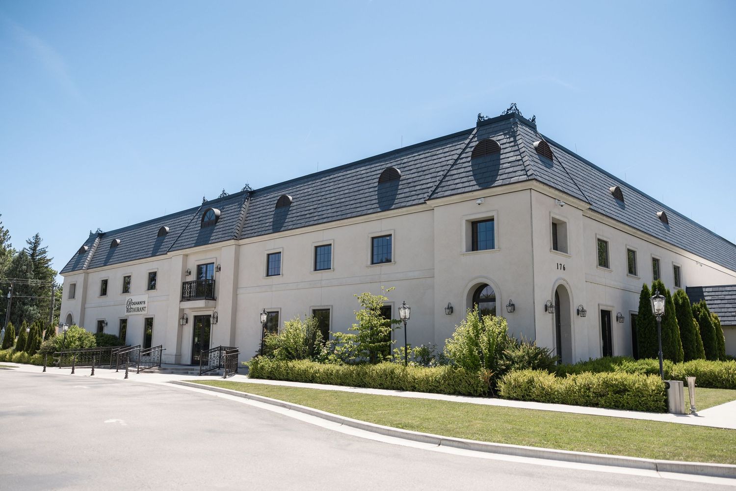 Exterior view of a large white wedding venue building with classic architecture on a sunny day.