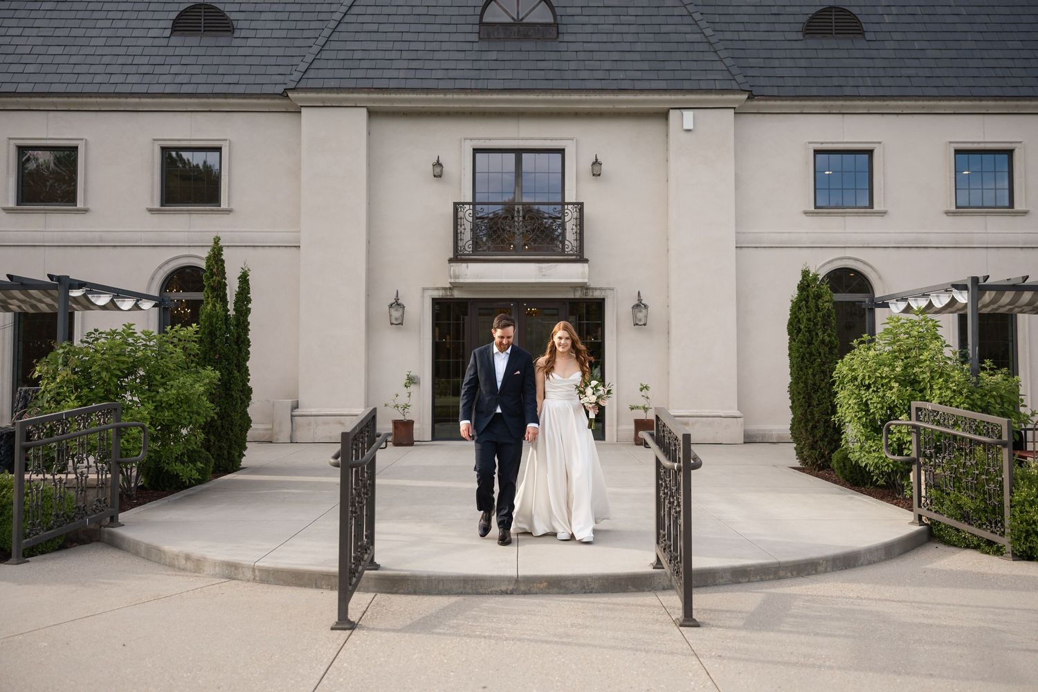Panoramic view of a wedding venue exterior with couple walking along a grand entrance.