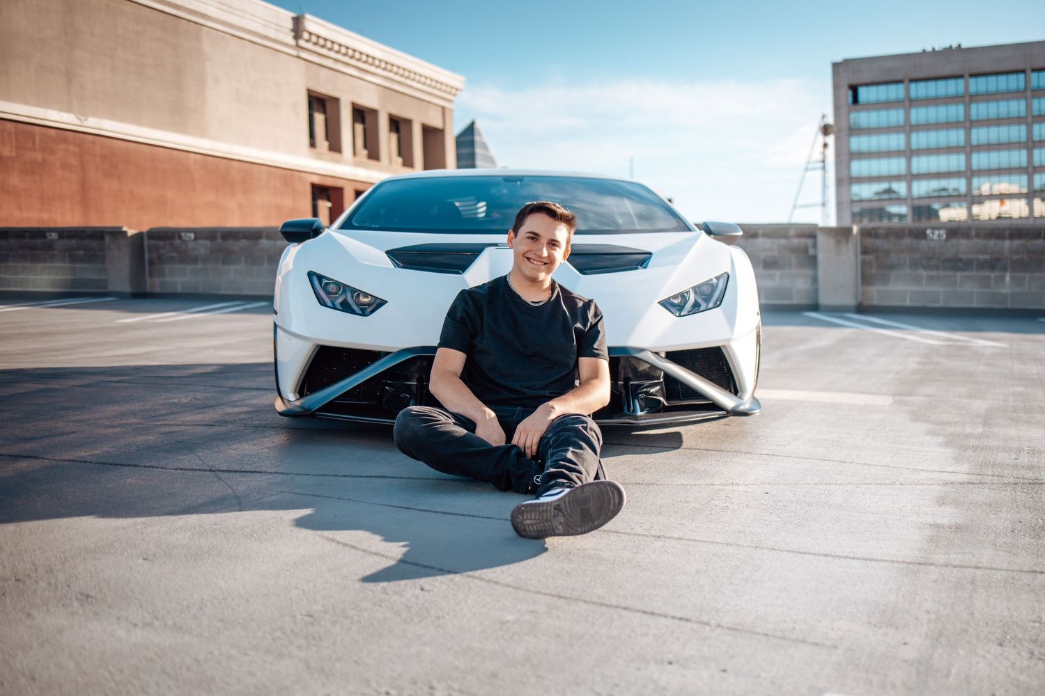 Urban automotive portrait with white Lamborghini Huracan on rooftop parking structure.