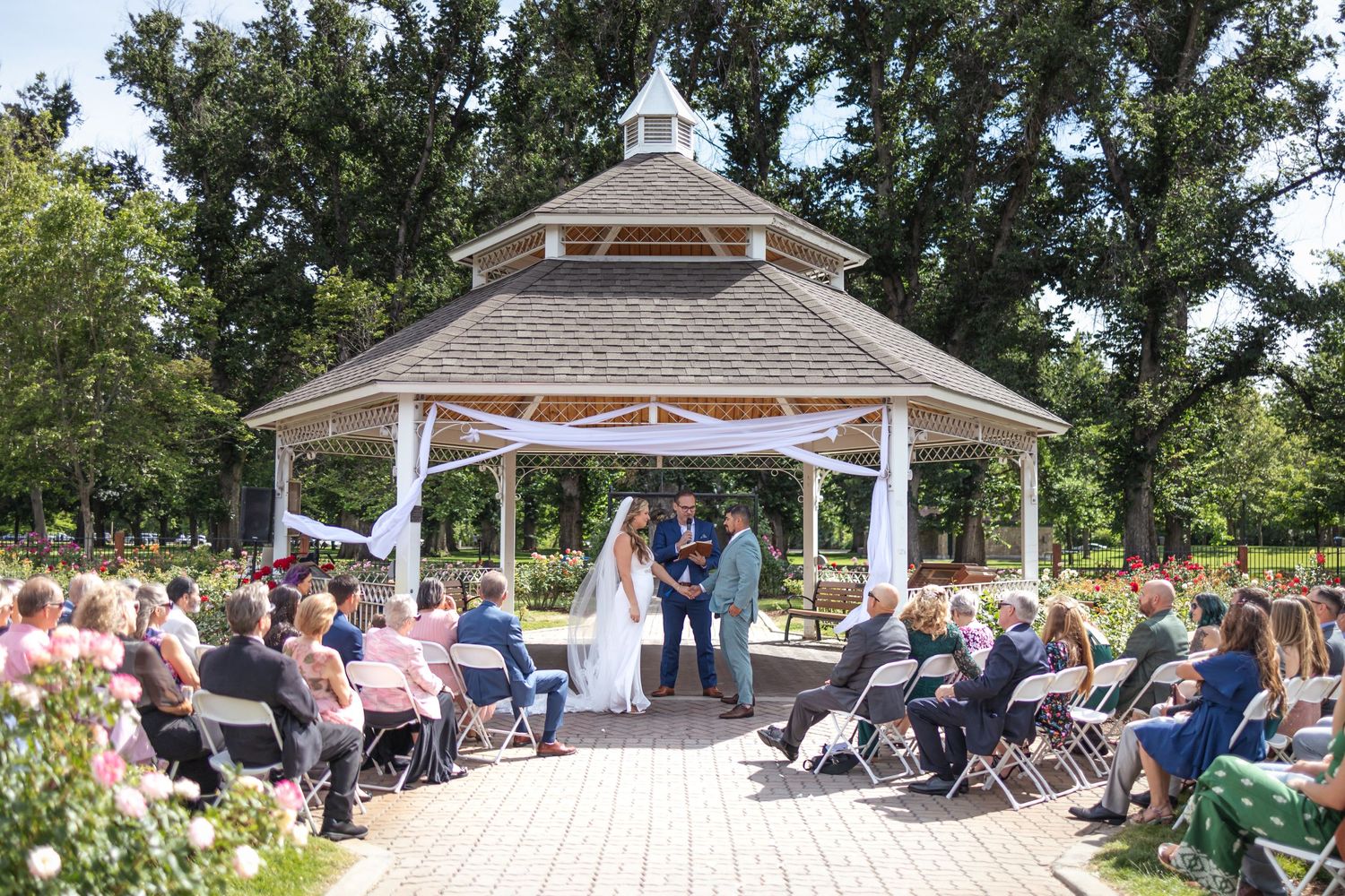 Panoramic view of outdoor wedding venue with white gazebo and guest seating.