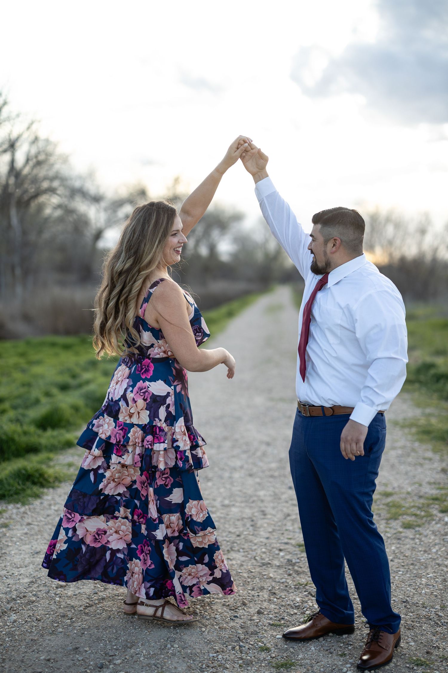 Joyful dancing poses captured on gravel path during golden hour.