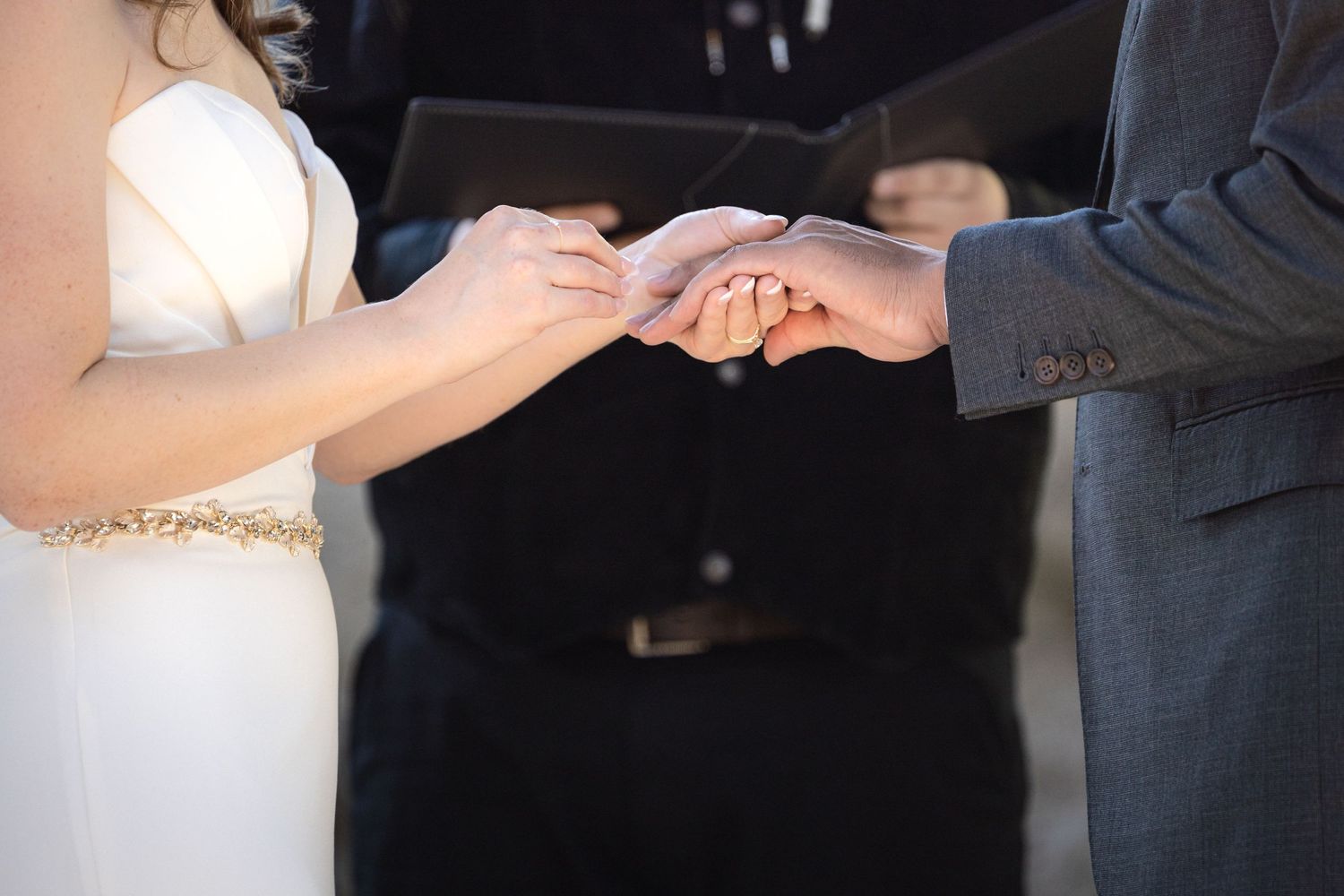 Close-up of hands exchanging rings during wedding ceremony.