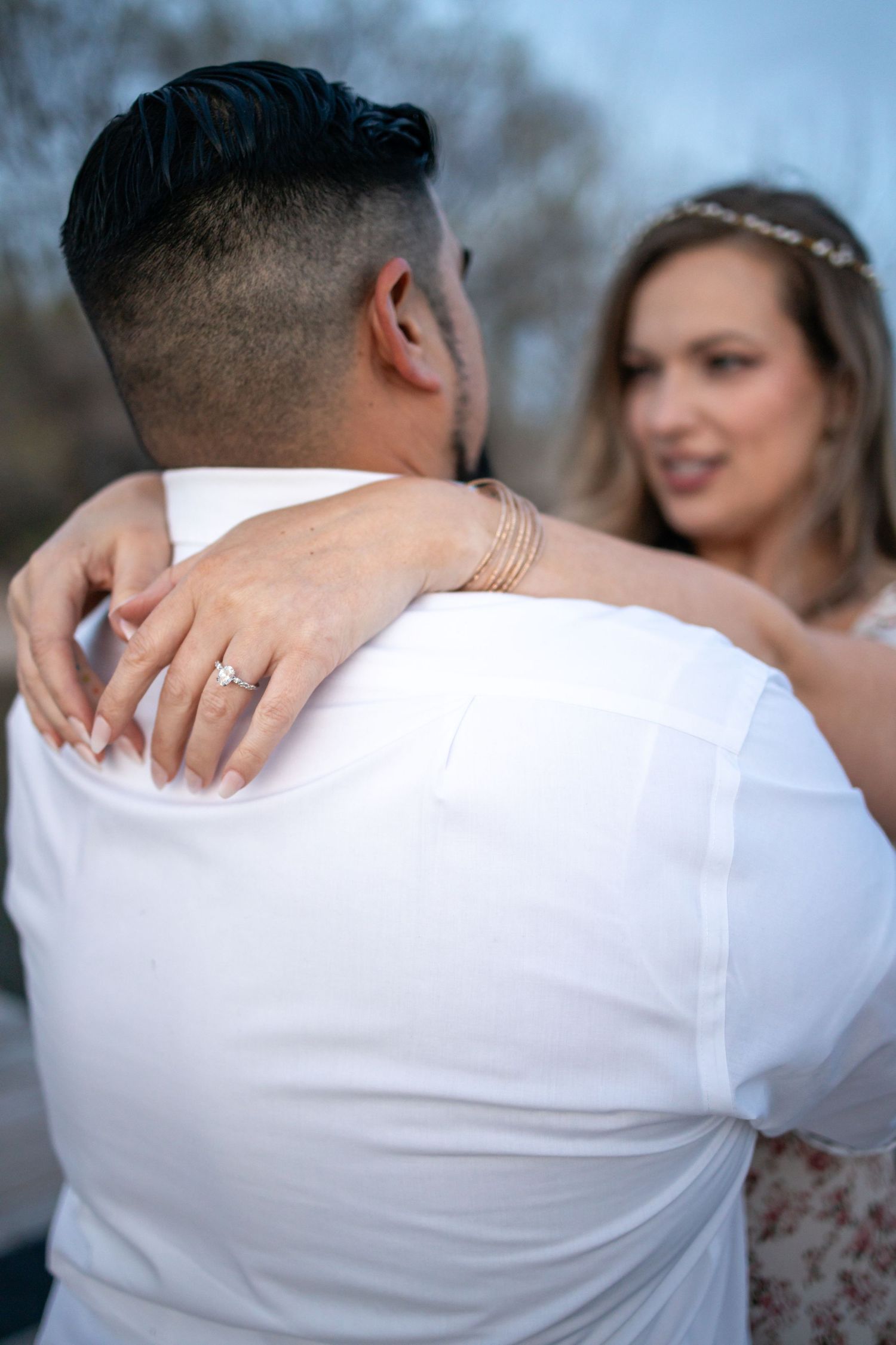 A close-up view of an embrace on a dock with a cloudy sky in the background.