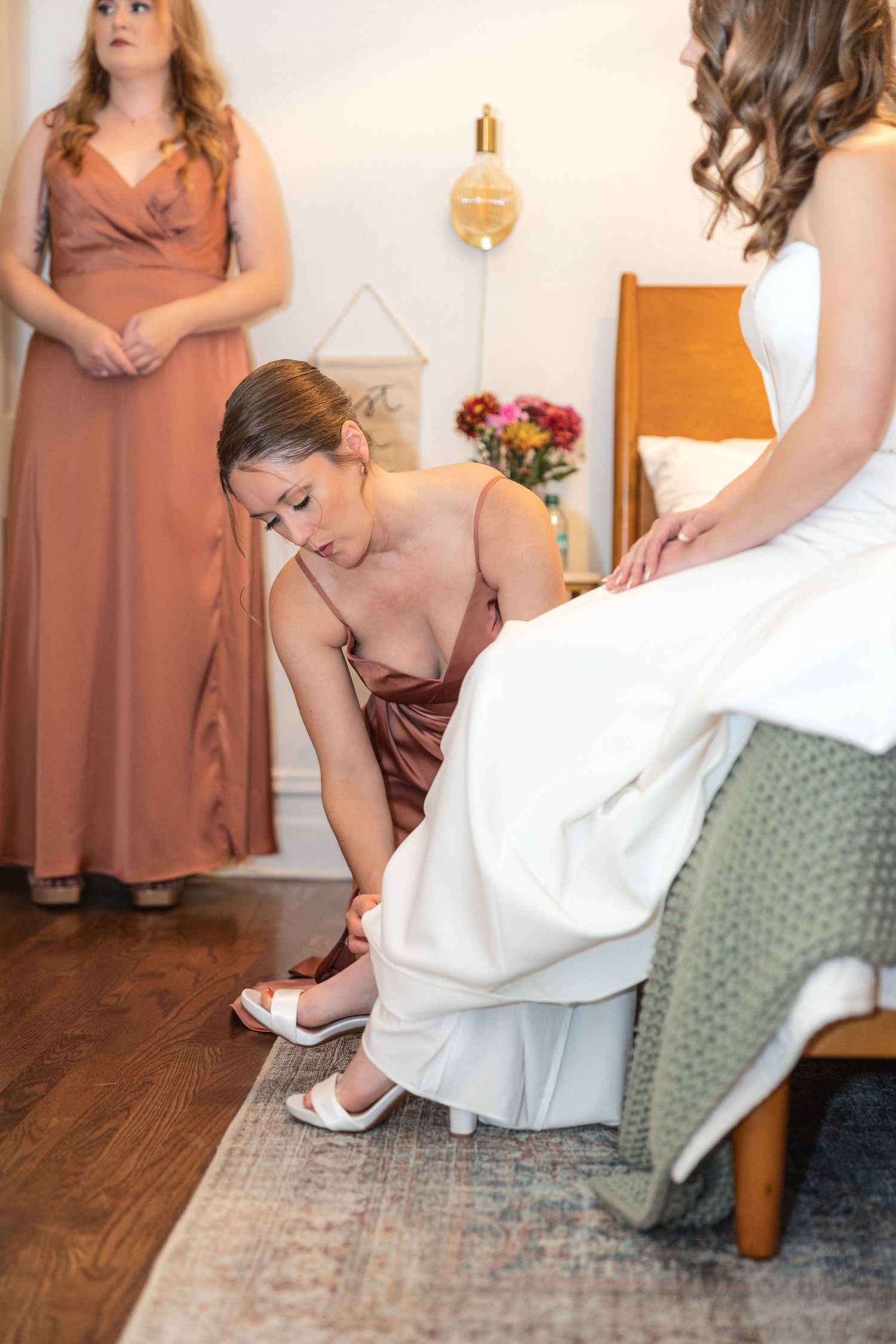 Final wedding dress adjustments with attendants in dusty rose dresses.