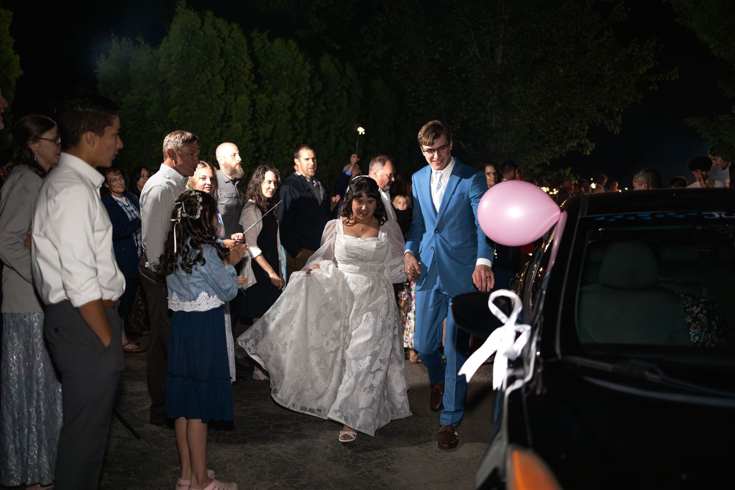 Wedding party members dancing and celebrating outdoors at night.
