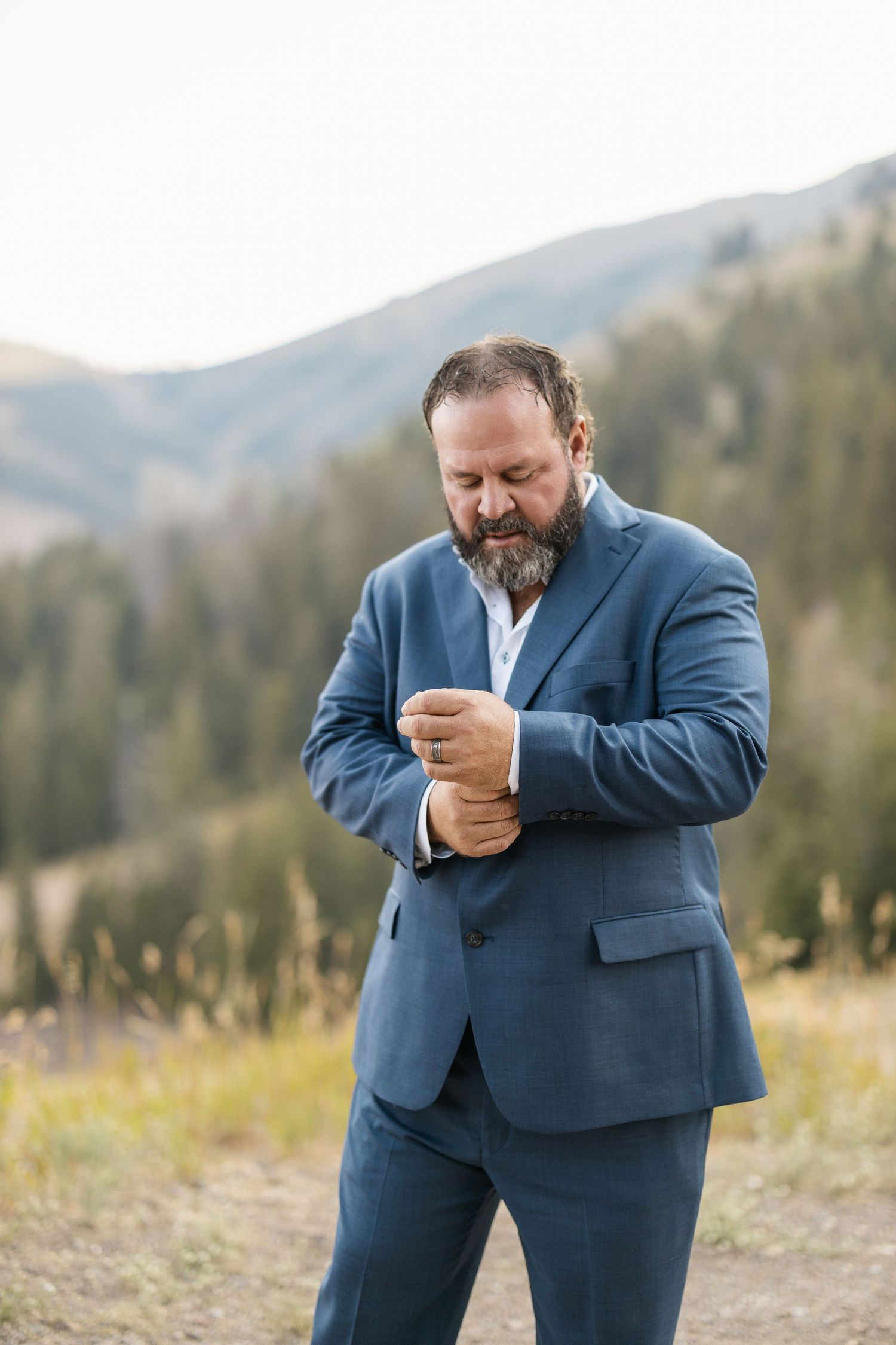 Series of emotional reactions in blue suit against mountain landscape.