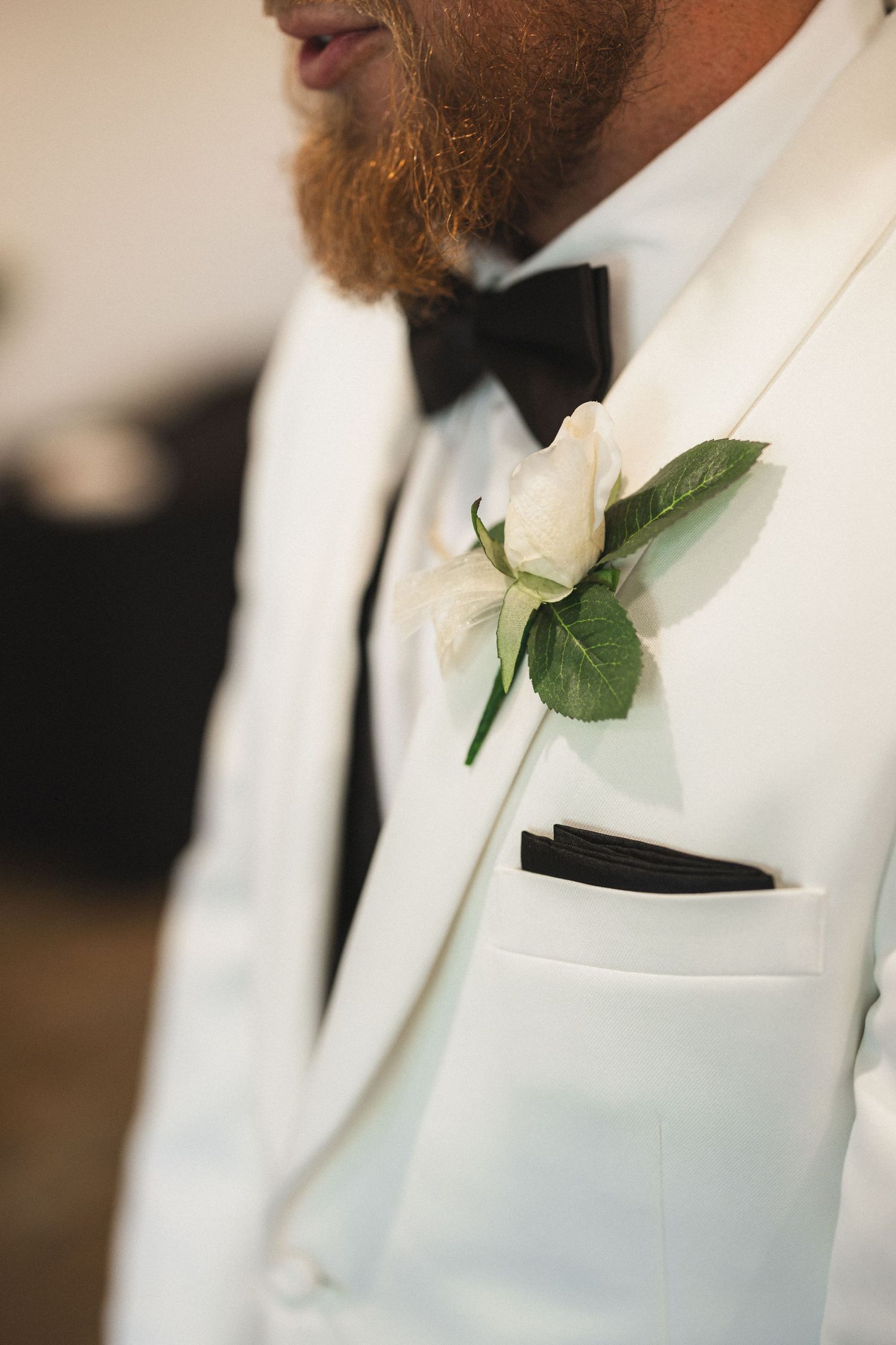 A detailed shot of a white boutonniere on a formal white tuxedo jacket.