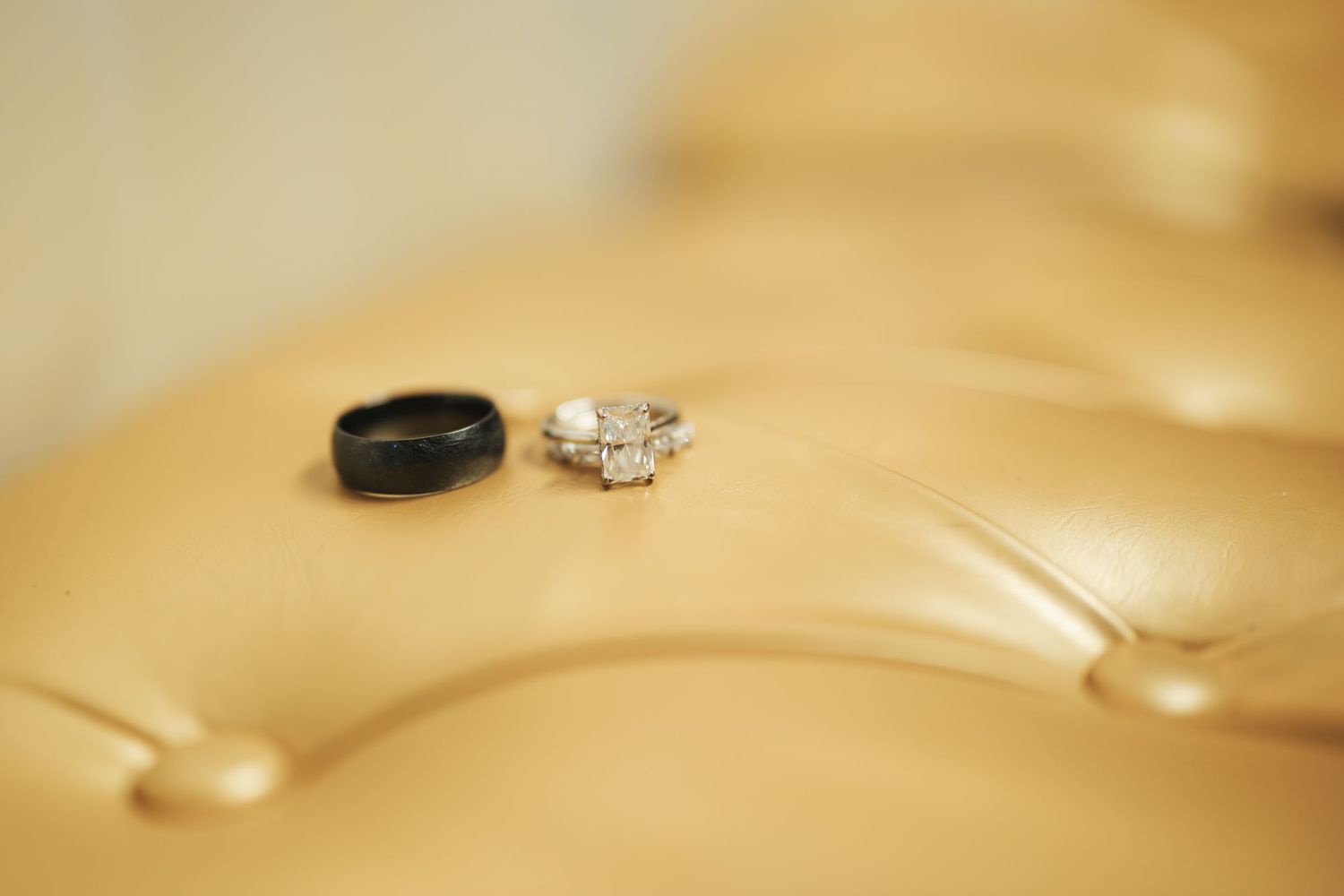 Wedding rings displayed on golden tufted surface.