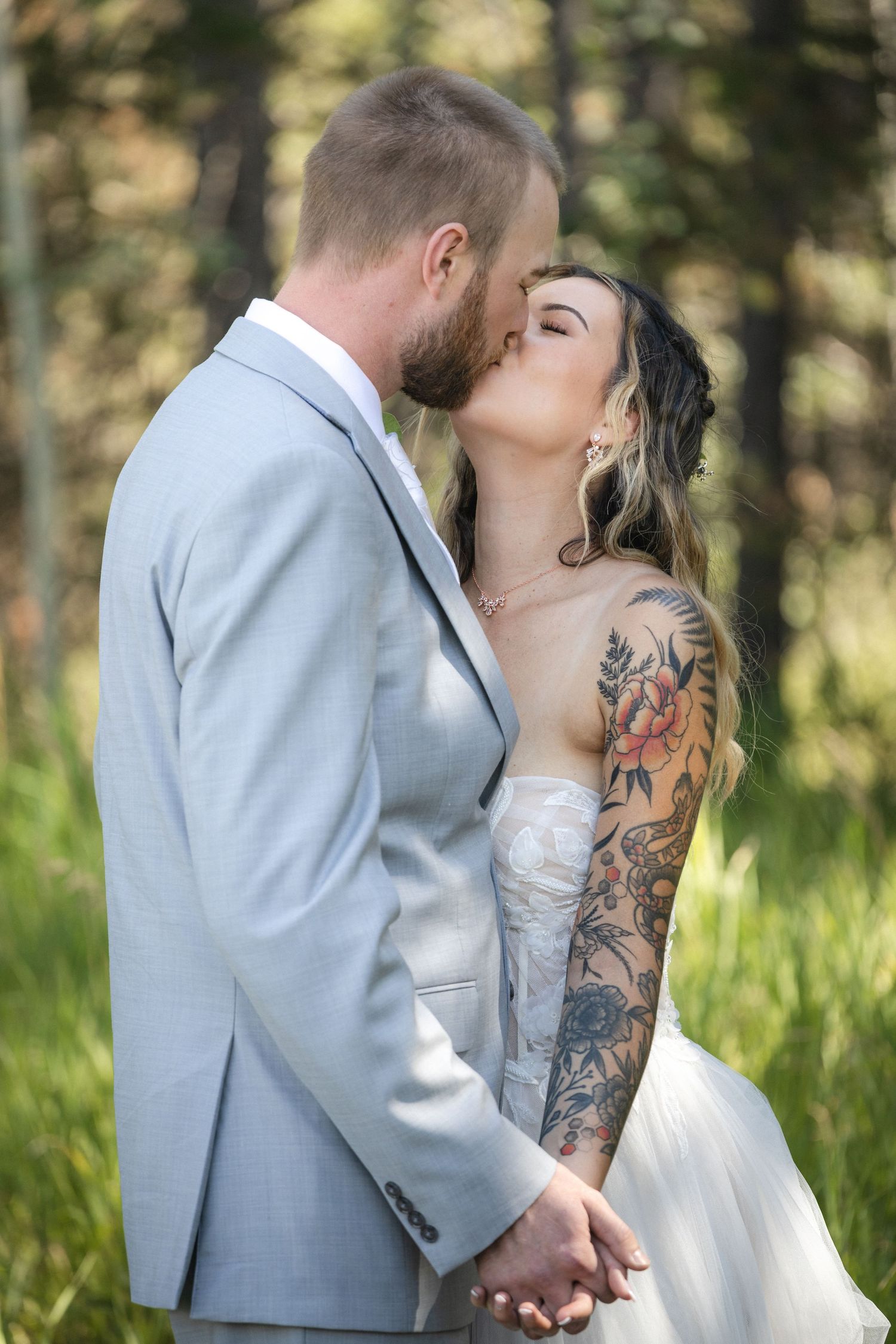 Romantic wedding couple shares tender moments in a sunlit forest setting.