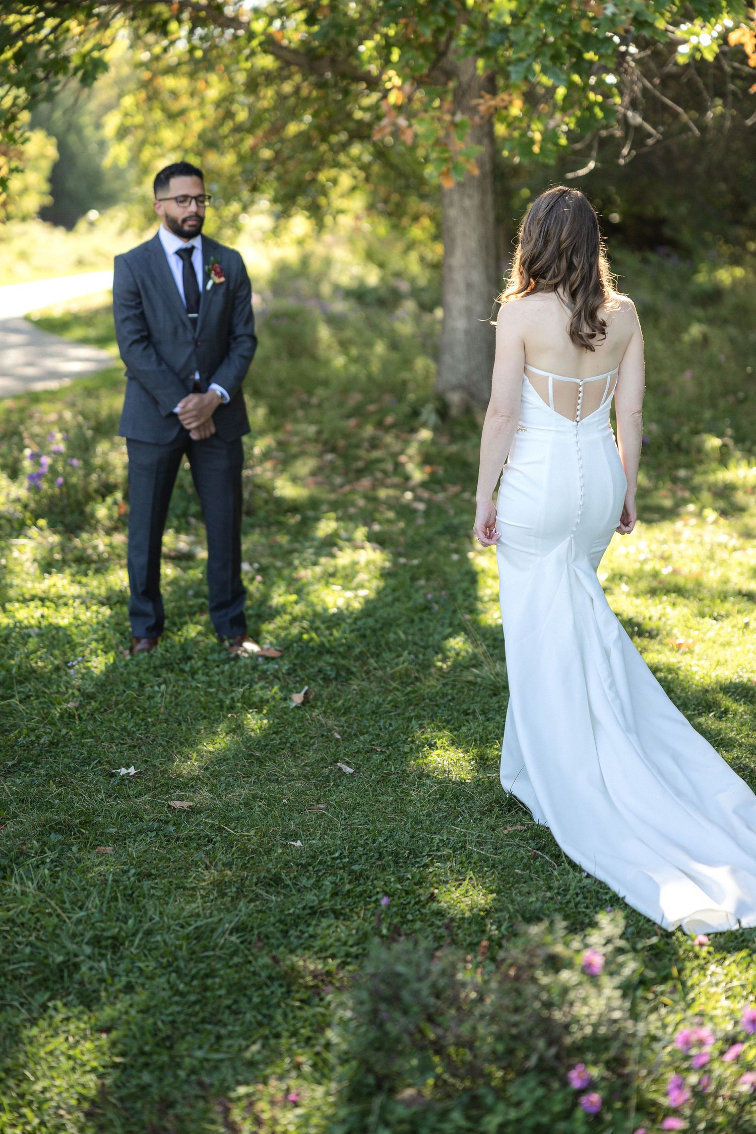 A garden wedding first look moment in dappled sunlight.