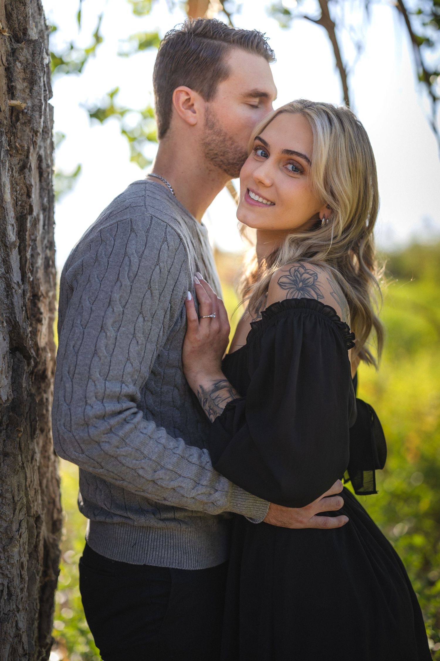 Intimate couple's portrait with golden sunlight filtering through trees.