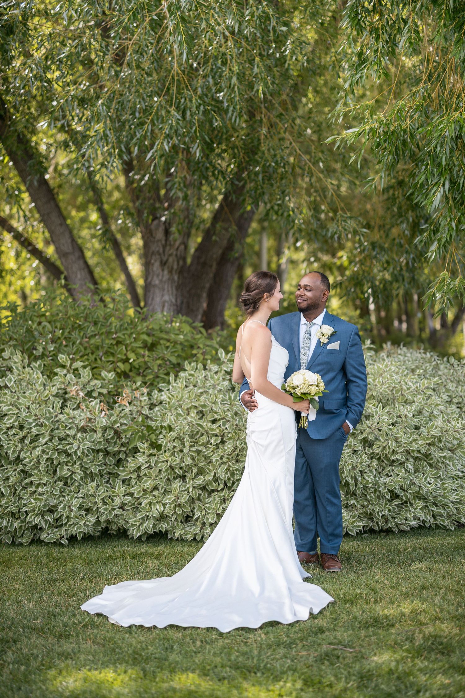 Wedding couple posing in garden setting with white dress and navy suit.