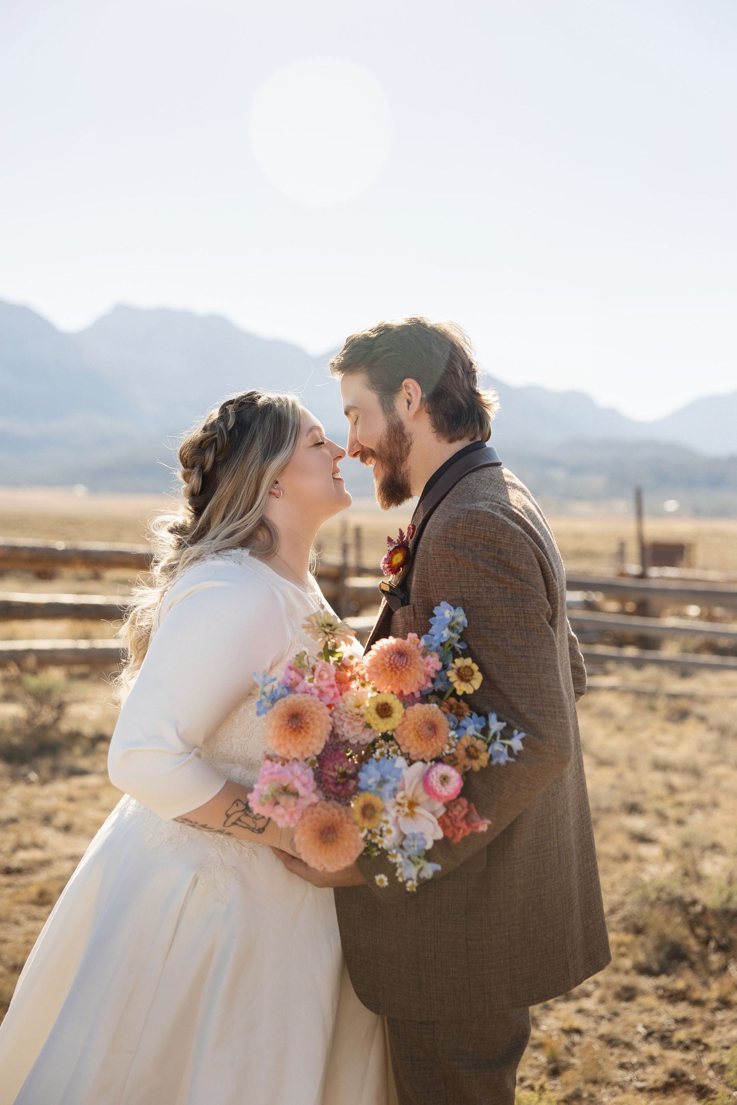 A romantic wedding moment captured in front of mountain scenery with a vibrant bouquet of wildflowers.
