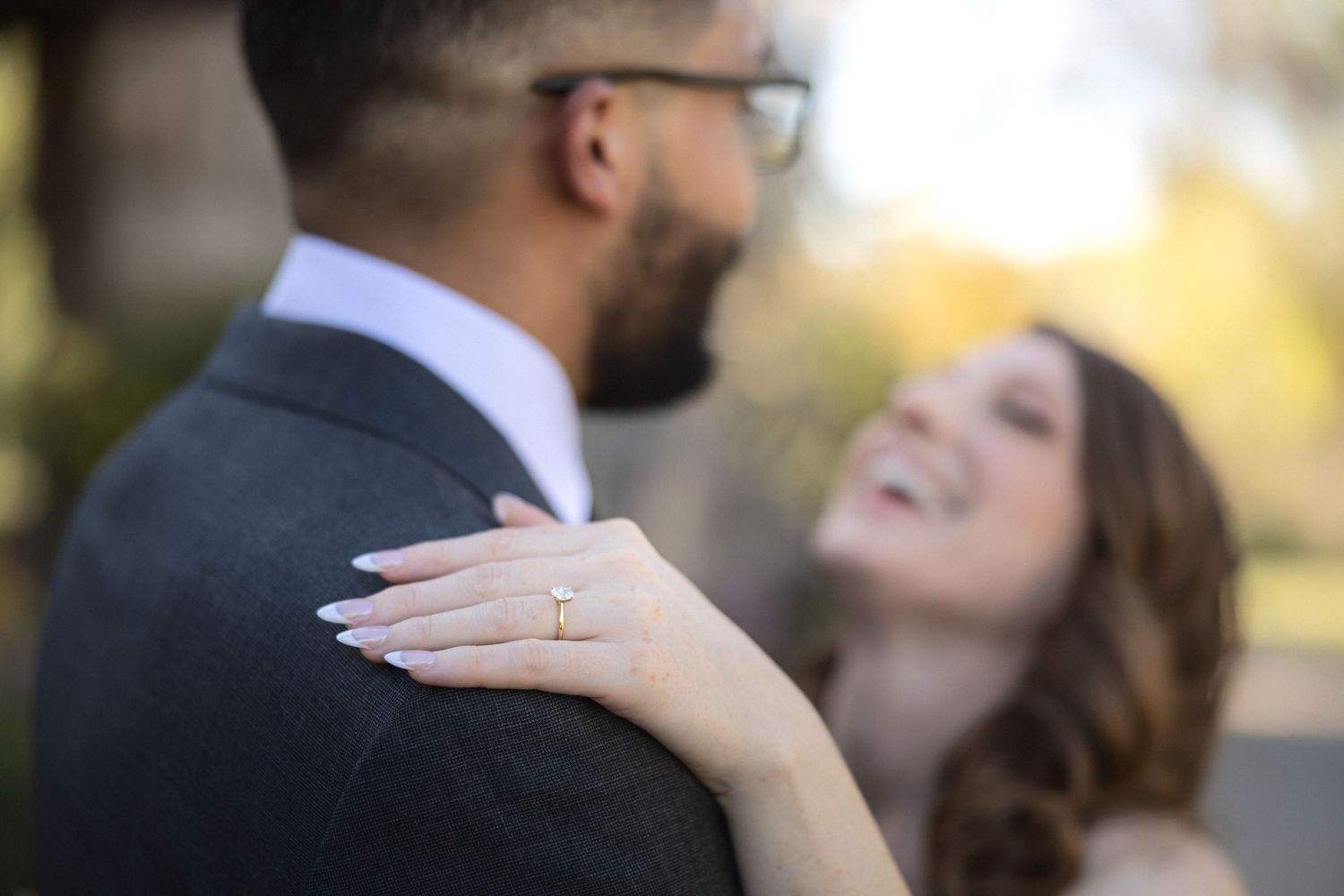 A romantic engagement portrait showing a close-up of a couple embracing as she displays her ring.
