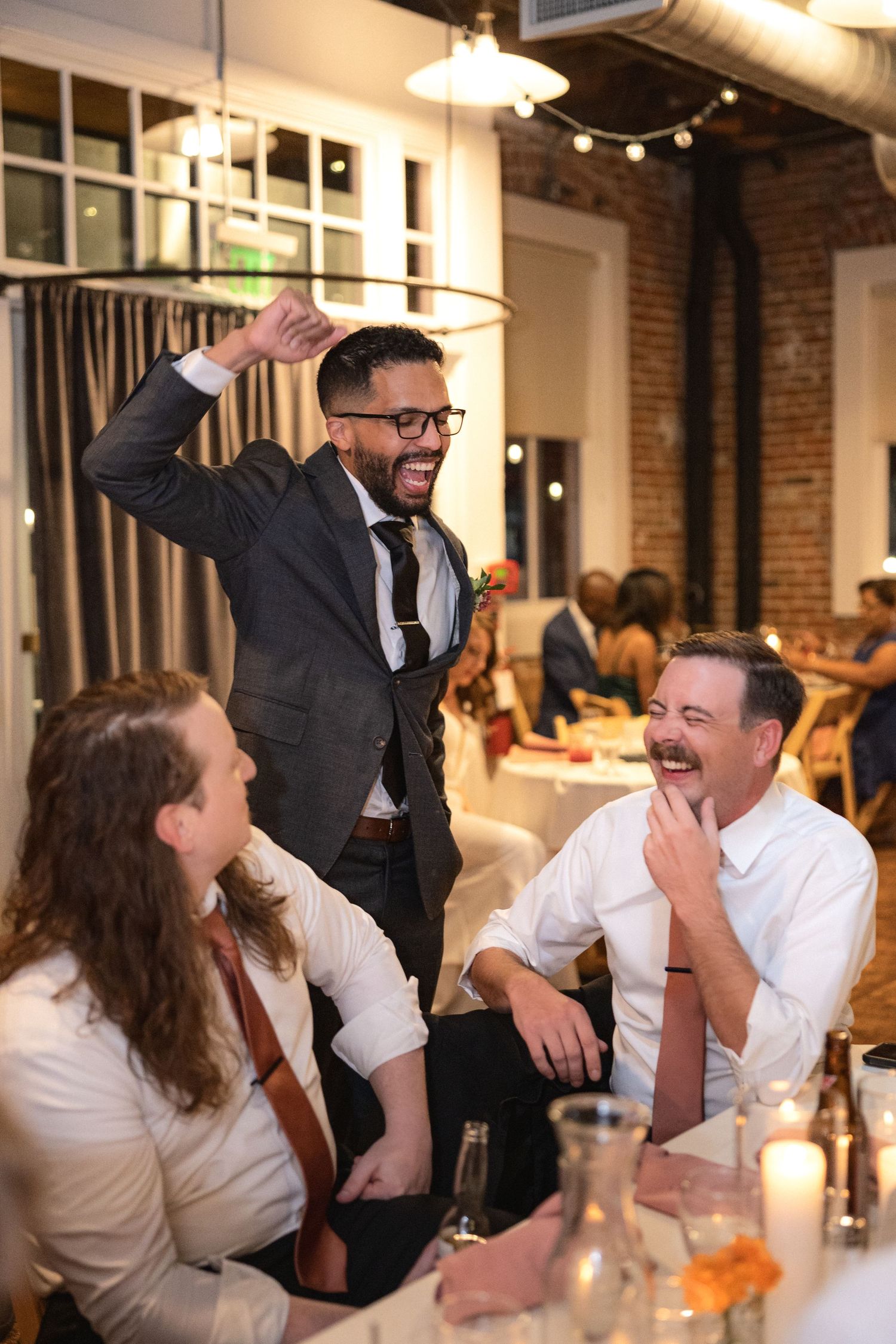Lively wedding reception moment in an industrial-style venue with exposed brick walls.