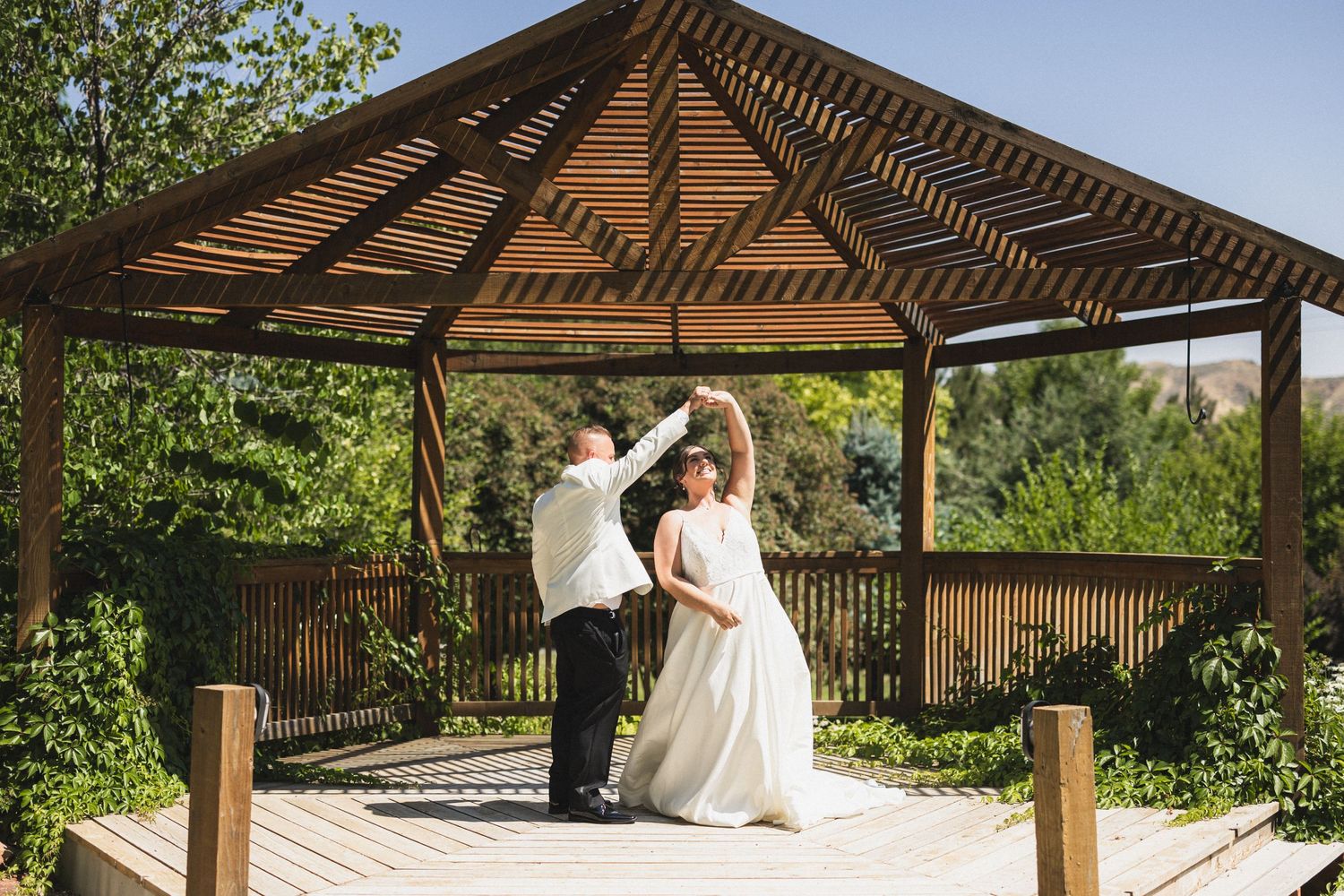 Couple dances under a wooden gazebo during their wedding celebration.