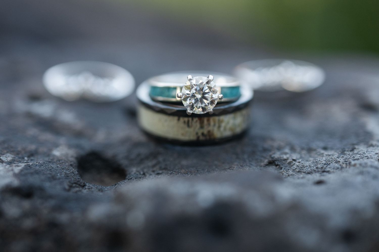A collection of engagement and wedding rings displayed on textured surfaces in varying lighting conditions.