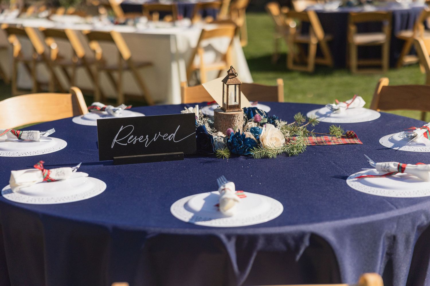 Wedding reception table set with navy blue linens and elegant place settings.