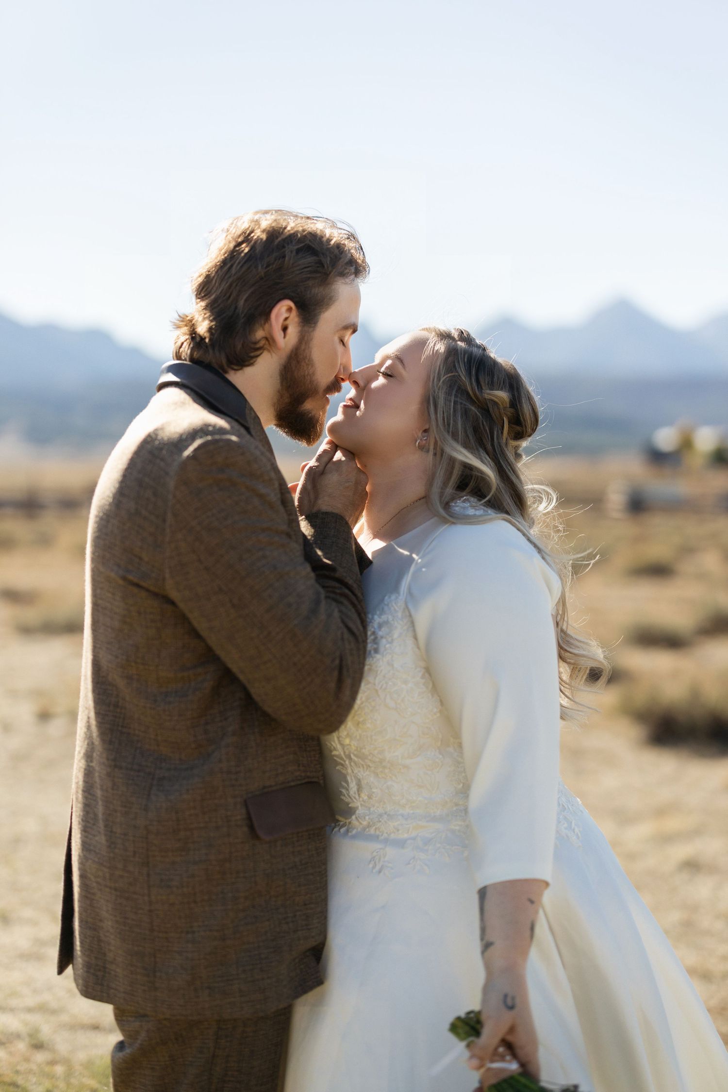 A romantic moment captured in a desert landscape with mountains in the background.