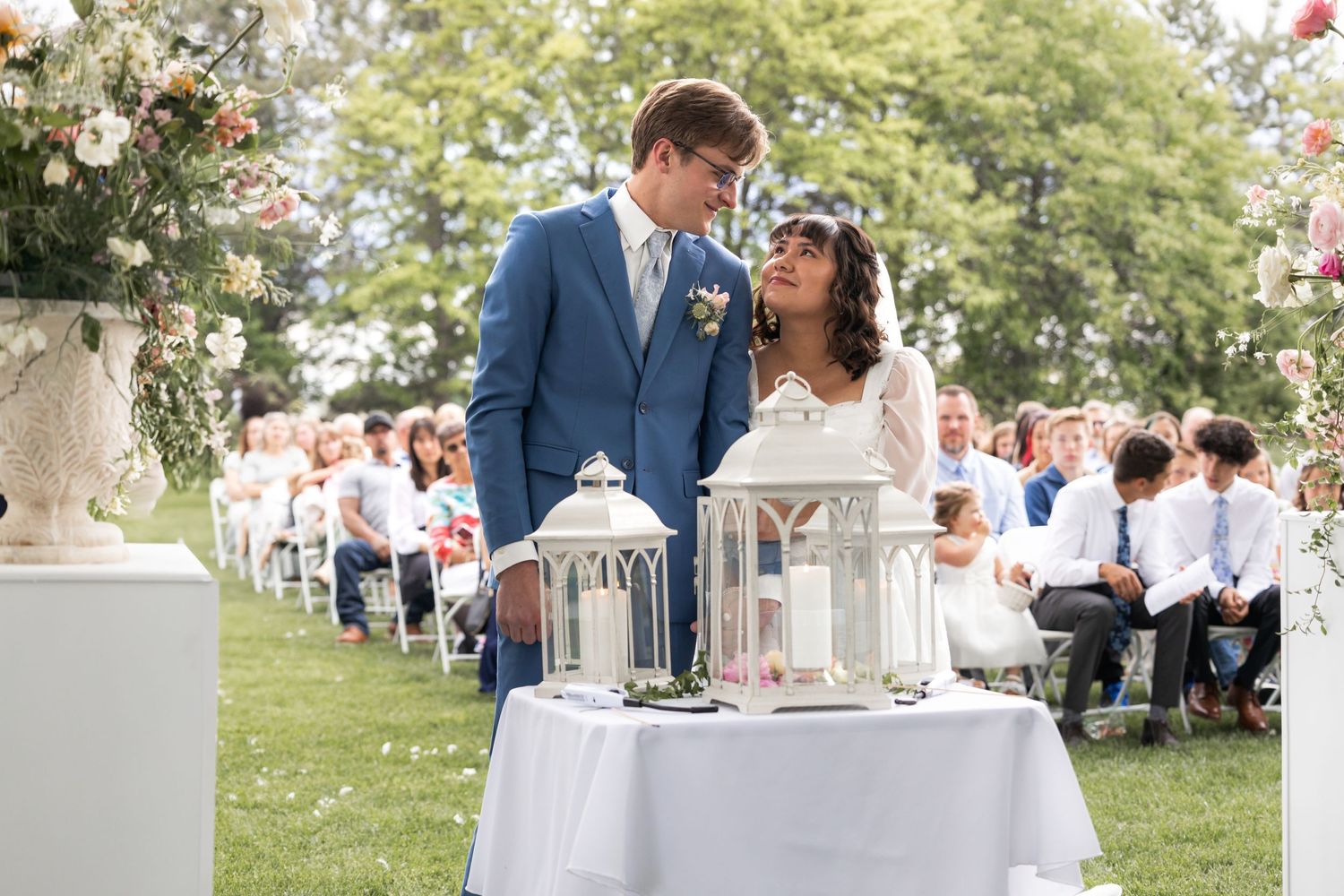 Newlyweds sharing intimate moment over decorative lanterns at outdoor garden wedding.