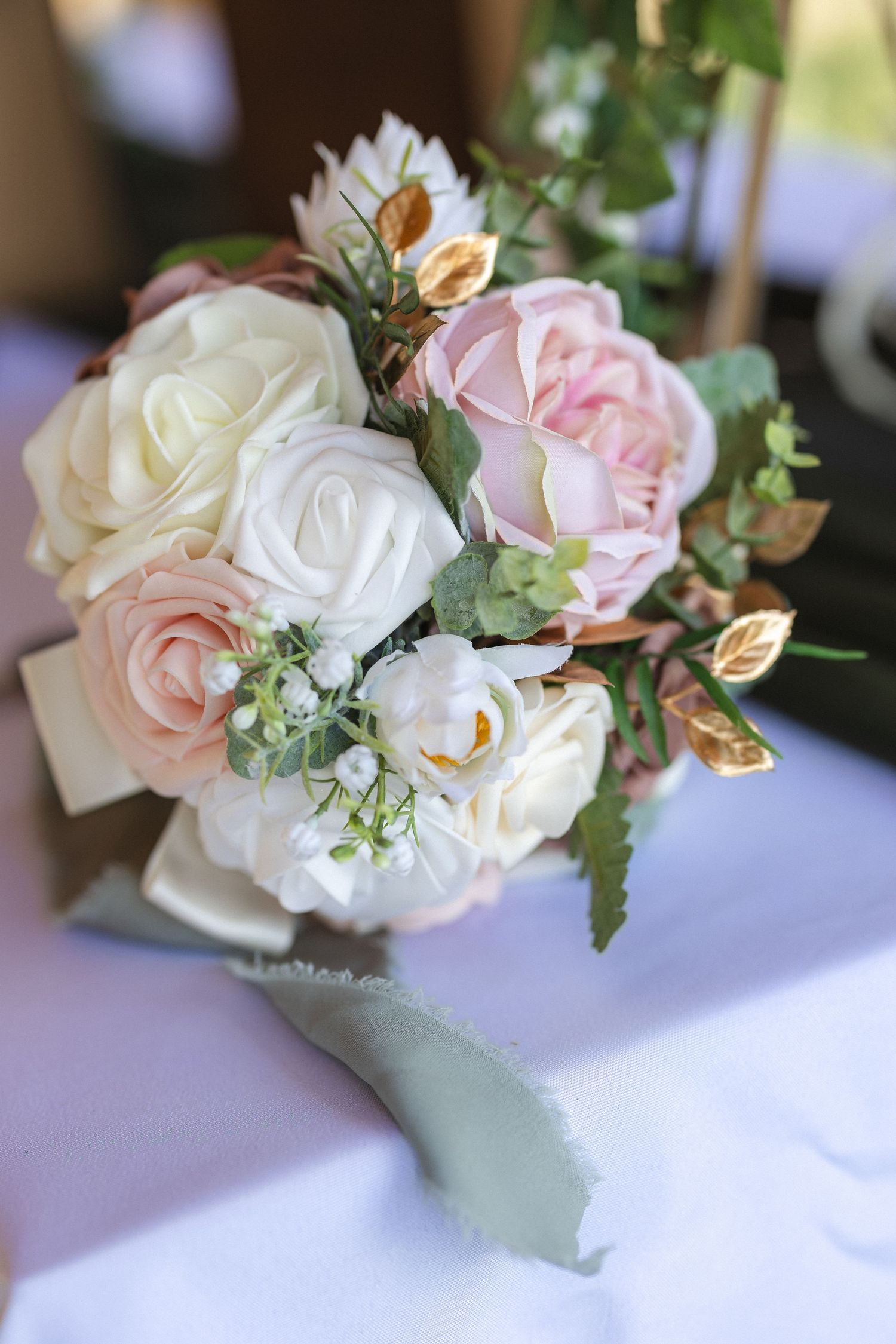 An elegant wedding bouquet featuring pink and white roses with delicate greenery accents.
