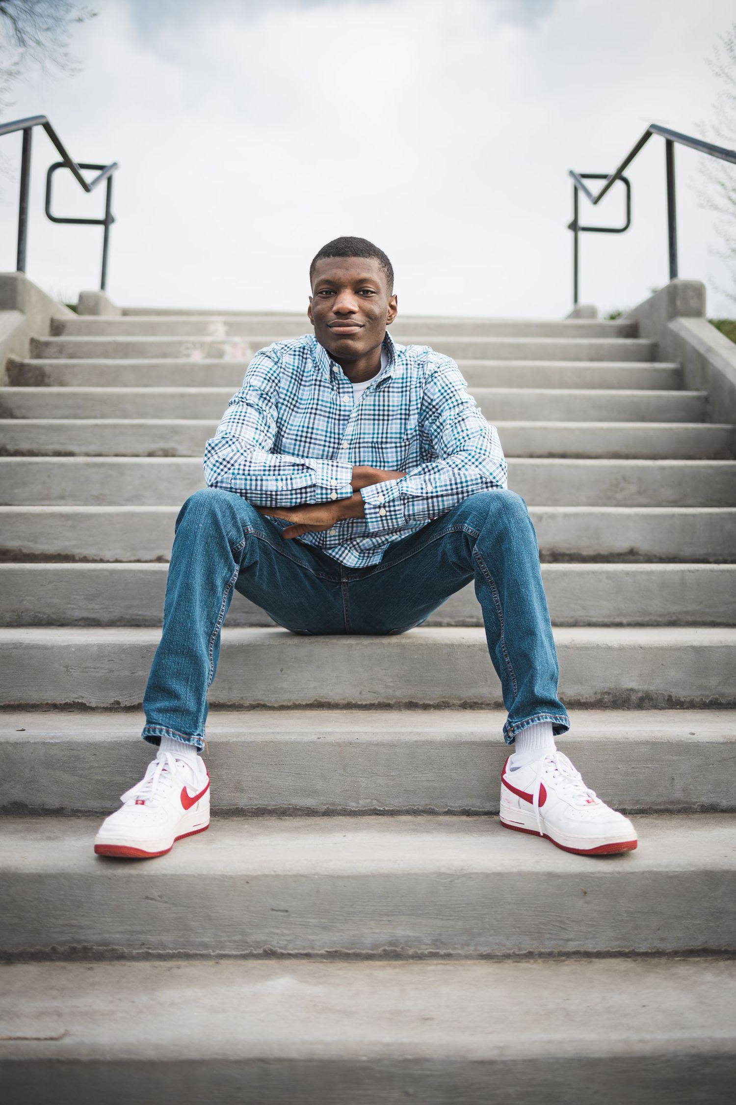 A series of connected images showing someone seated on concrete steps wearing jeans and white Nike sneakers.
