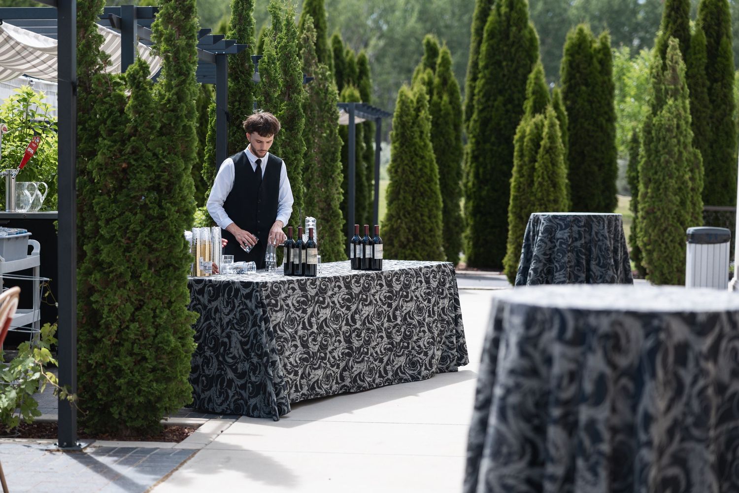 Manicured garden venue with tall cypress trees and stone walls creating an elegant outdoor setting.