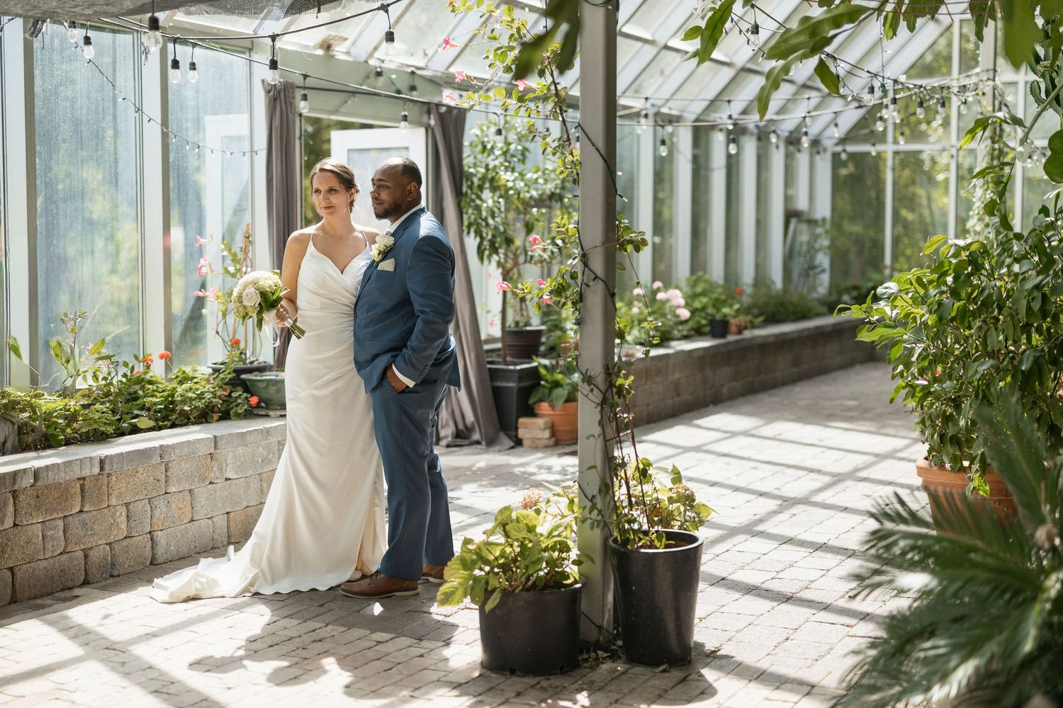 Sun-drenched greenhouse wedding photos with glass panels and lush plants creating a natural backdrop.