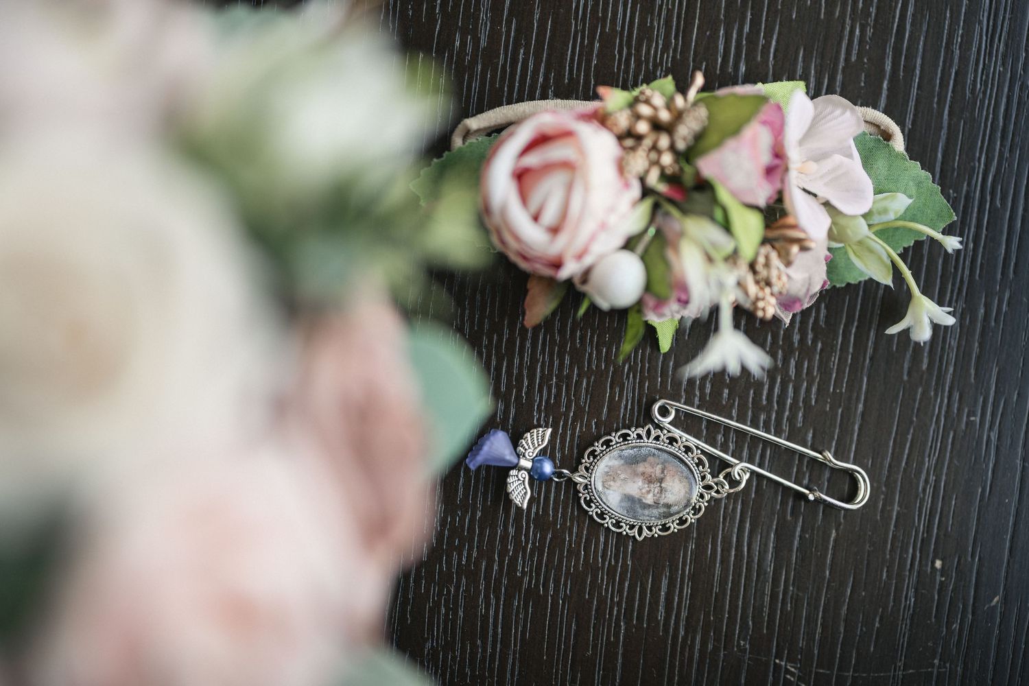 Delicate pink floral hair accessory with vintage brooch pin on dark background.