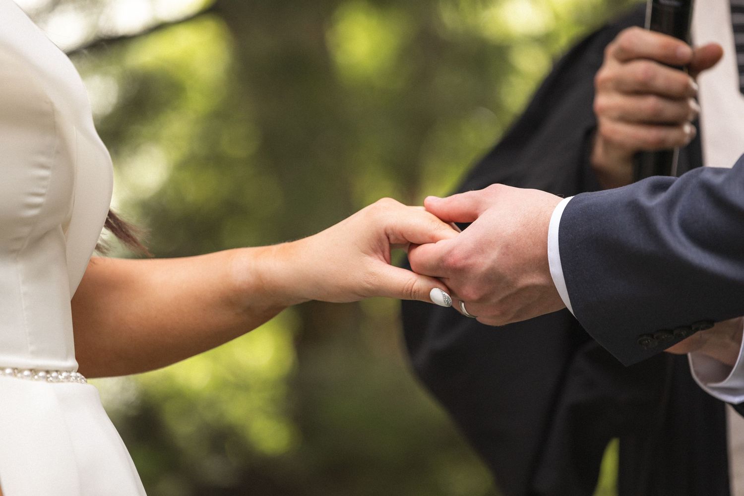 Intimate capture of hands during wedding ring exchange ceremony.