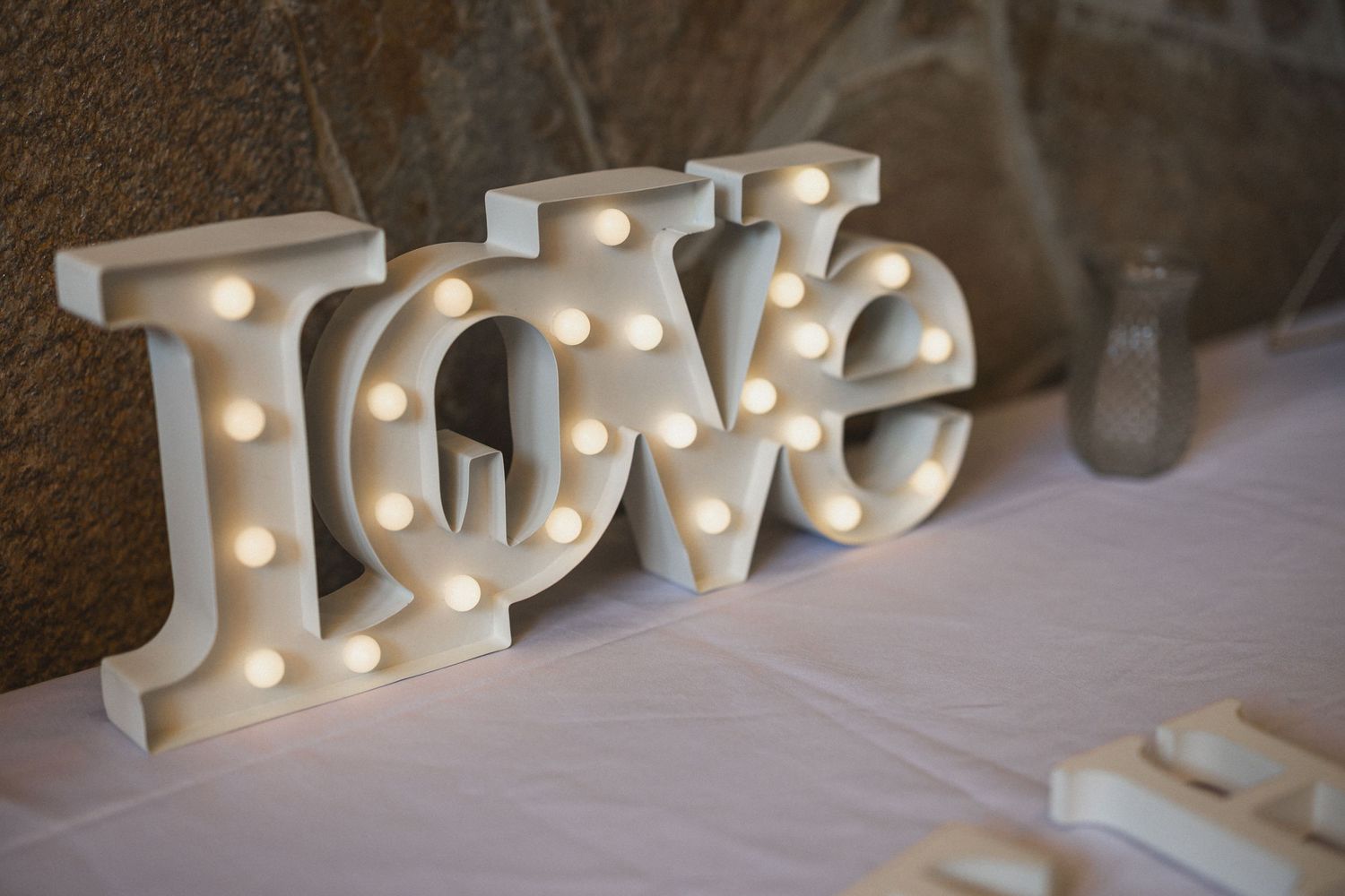 Illuminated white LOVE marquee letters displayed on wedding reception table.