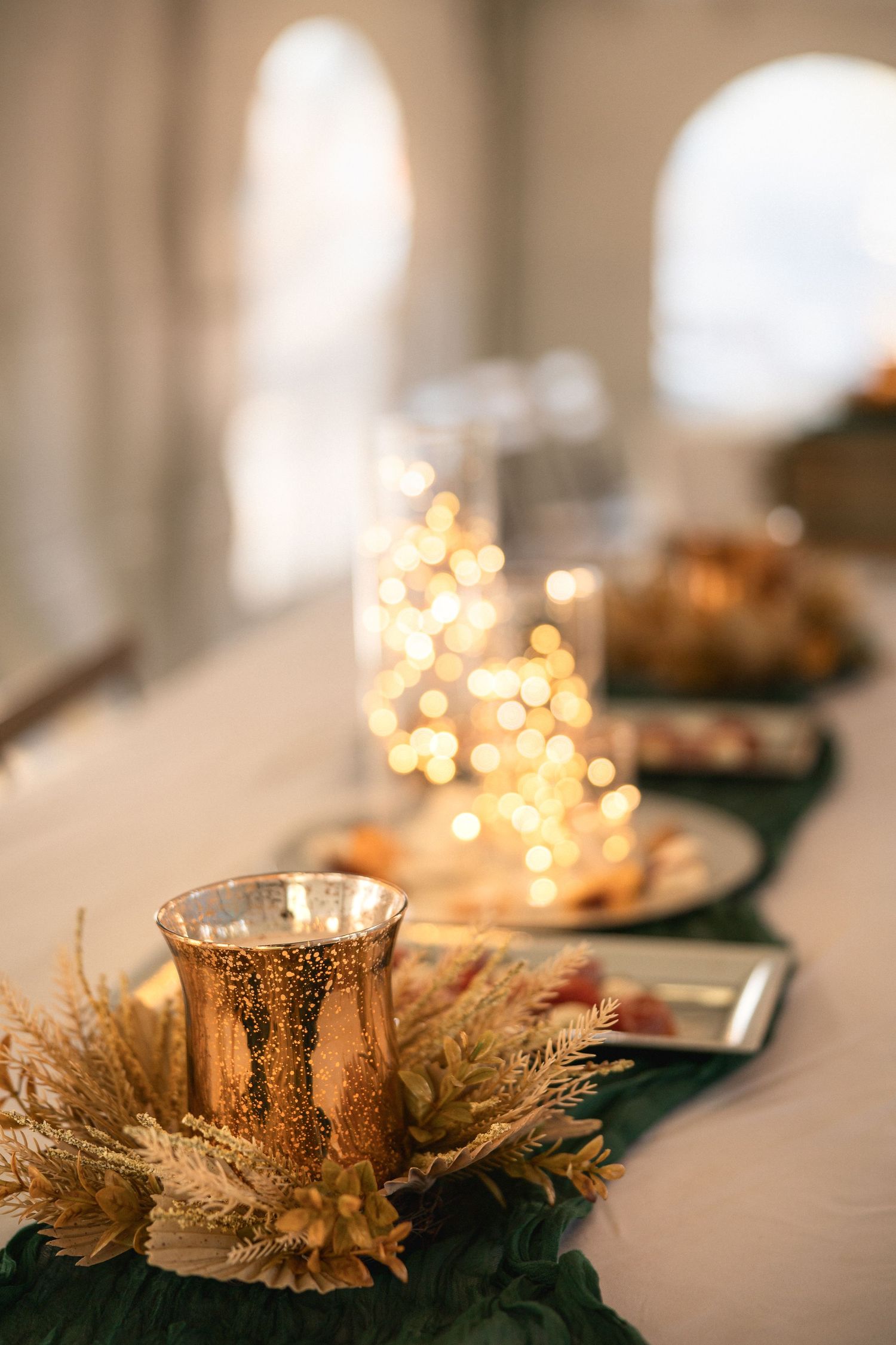 Elegant table decor featuring mercury glass votives and dried wheat arrangements with soft bokeh lighting.
