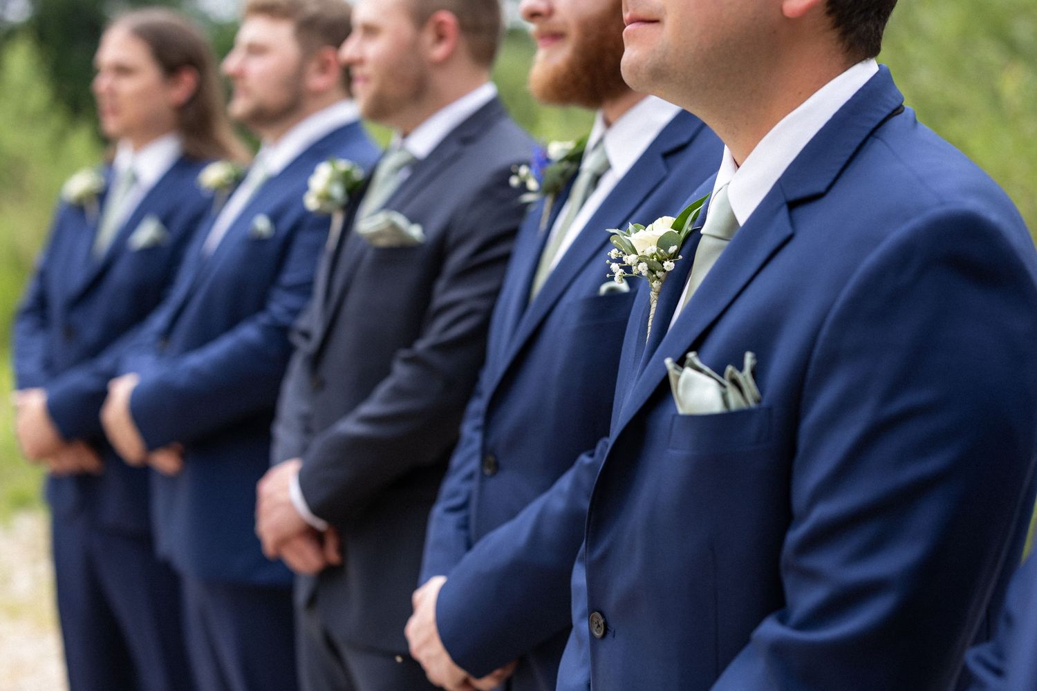 Close-up profile view of groomsmen in navy suits with pocket squares.