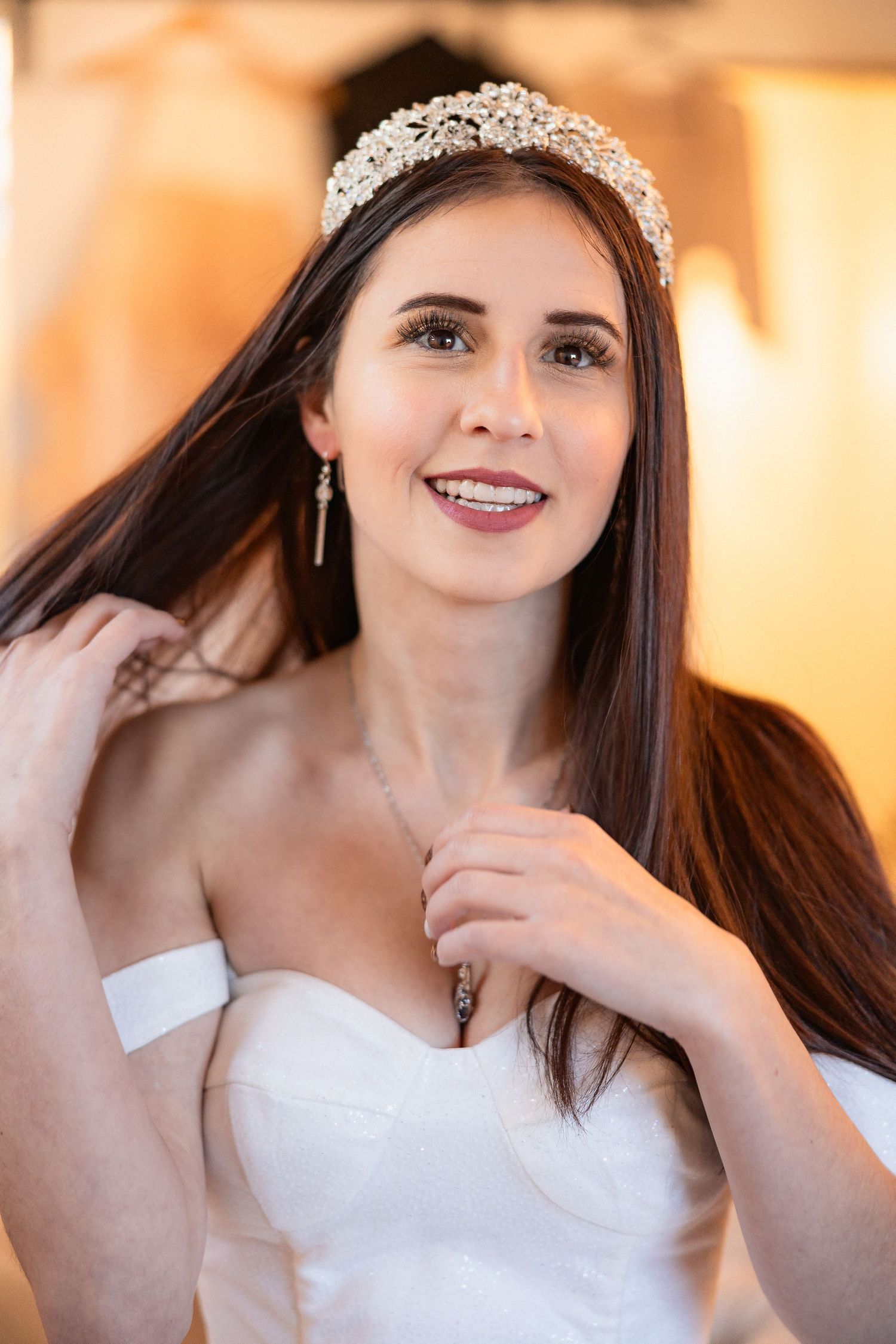 A bride in a strapless wedding gown smiles while wearing an ornate crystal tiara.