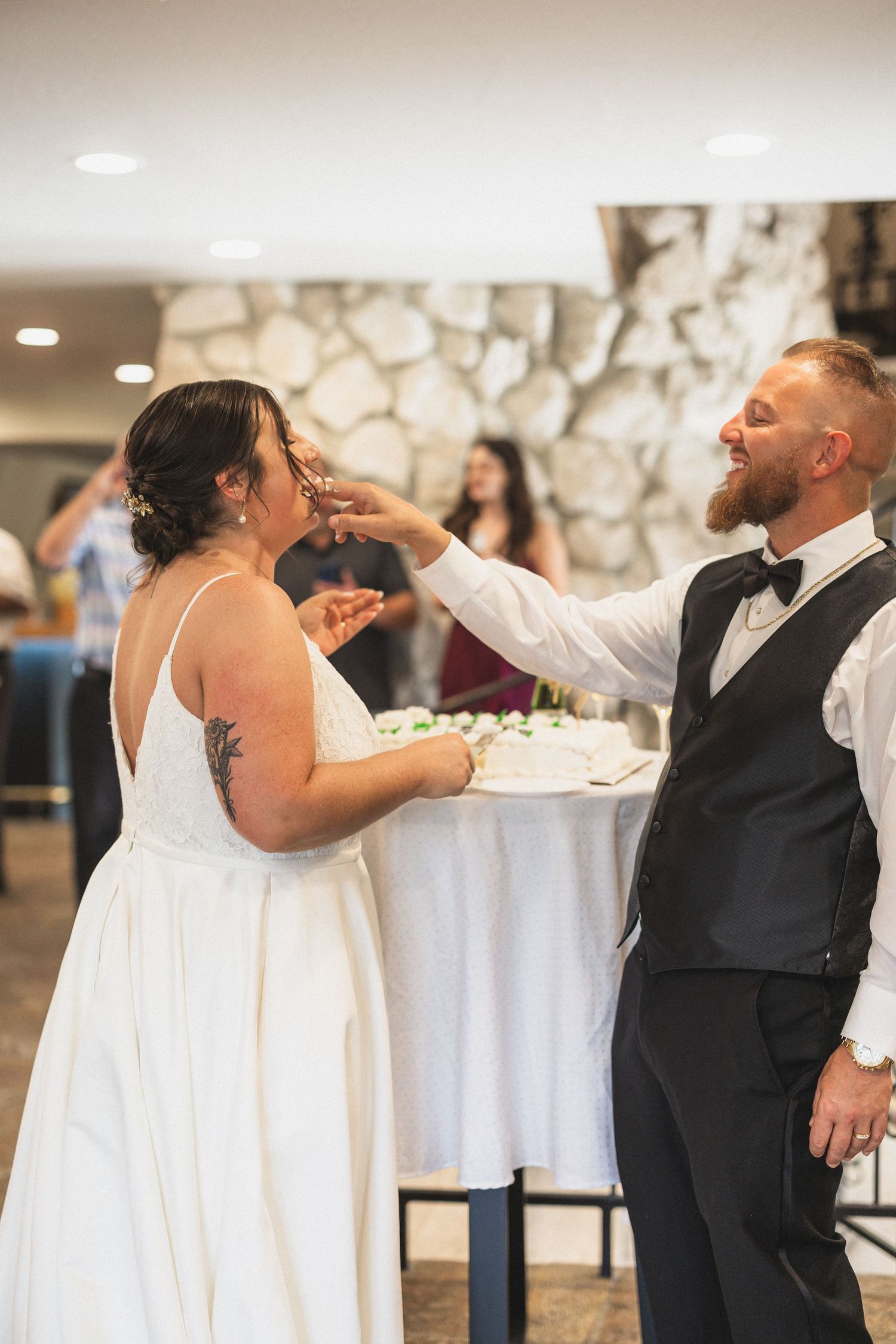 The couple shares wedding cake during a traditional cake-cutting moment at their reception.