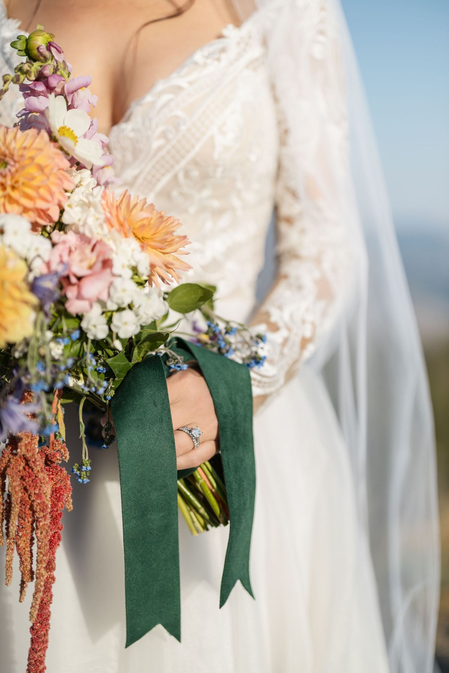 Wedding bouquet with colorful dahlias and flowers wrapped in green ribbon.