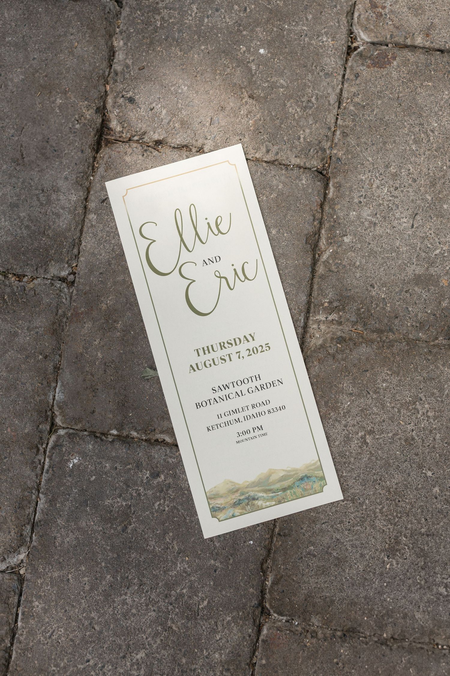 Wedding invitation with elegant script text lying on concrete ground.