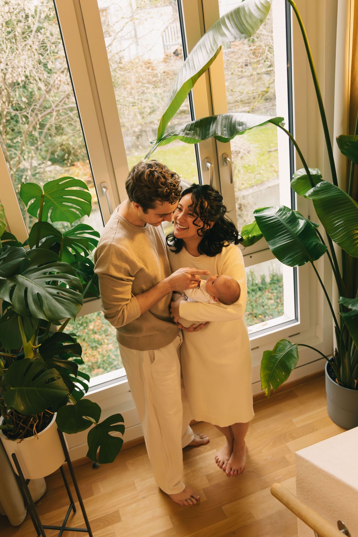 Parents standing with their newborn on the stairs at home during a lifestyle newborn photoshoot.