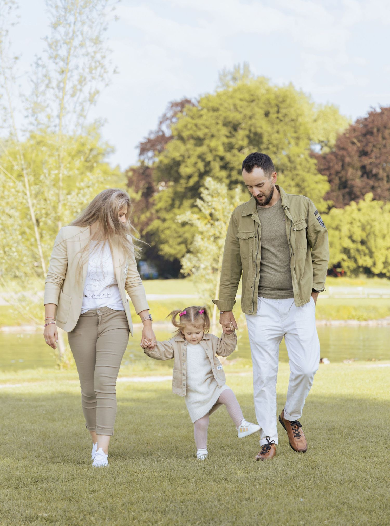 Parents walking with their daughter in a park during a relaxed family photoshoot in Switzerland.