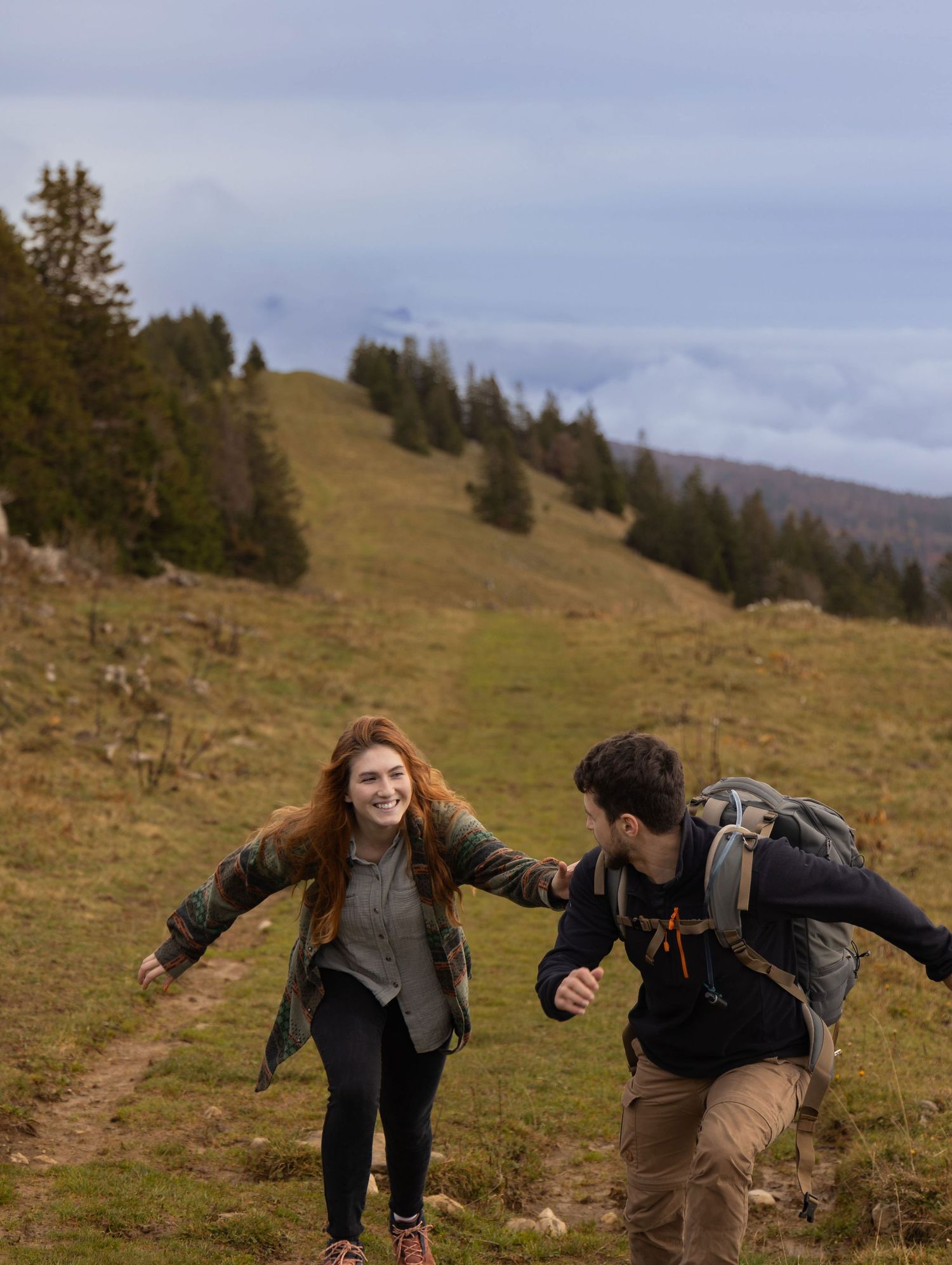 Young couple playing together in the mountains during an adventurous couples photoshoot.