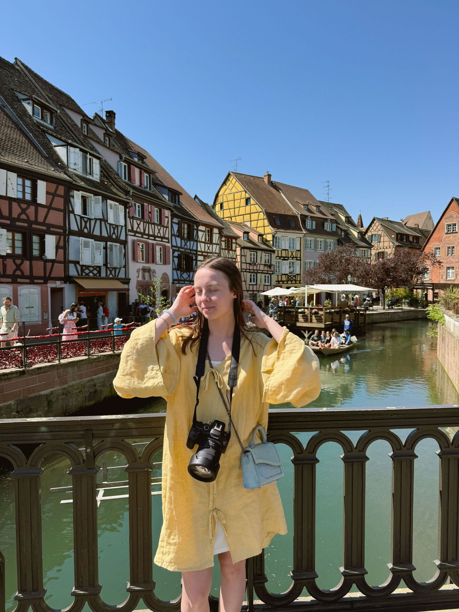 Portrait of a photographer in a yellow dress with colourful houses in the background.