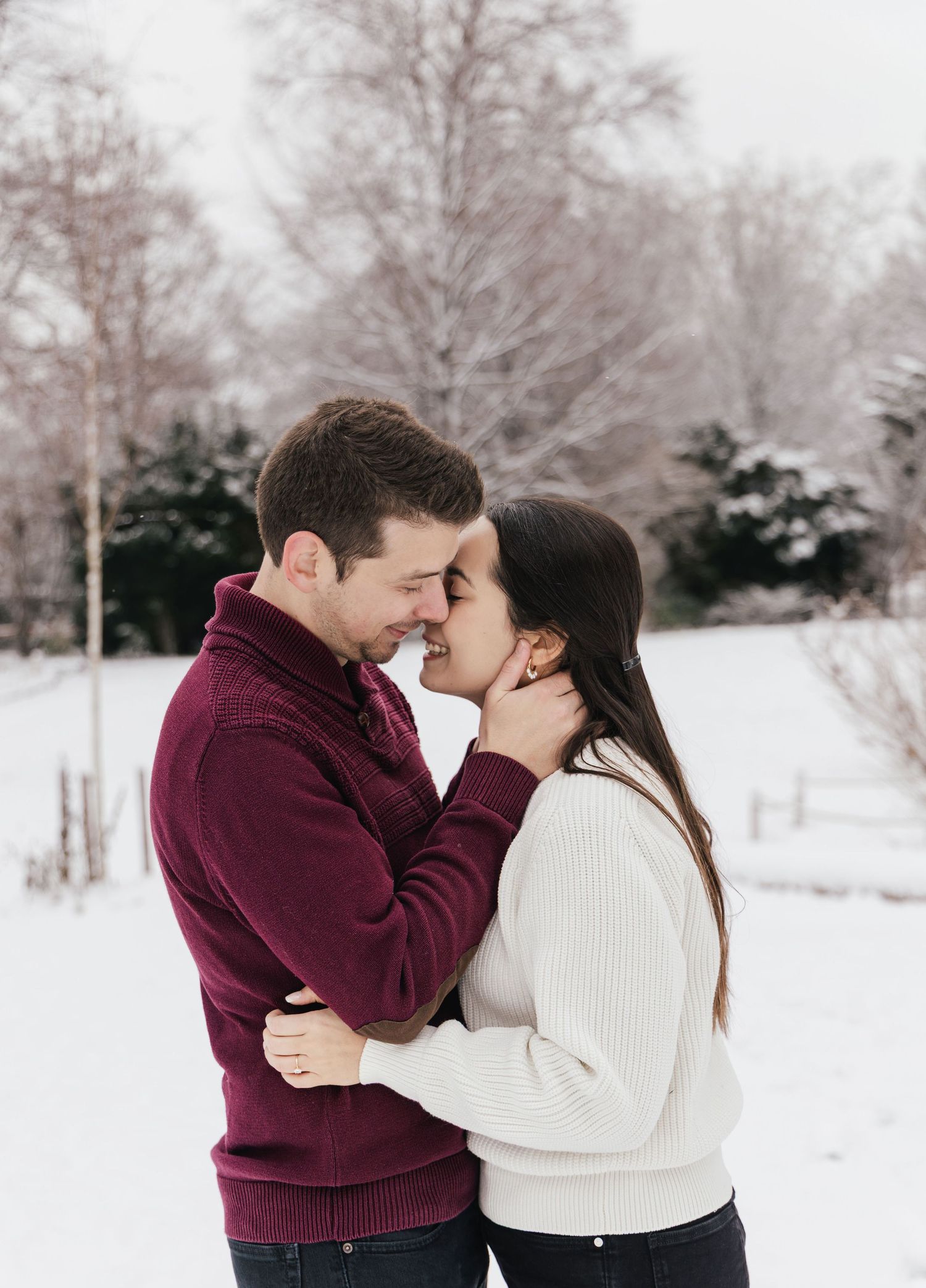 Couple hugging and kissing in the snow during an intimate winter photoshoot in Switzerland.