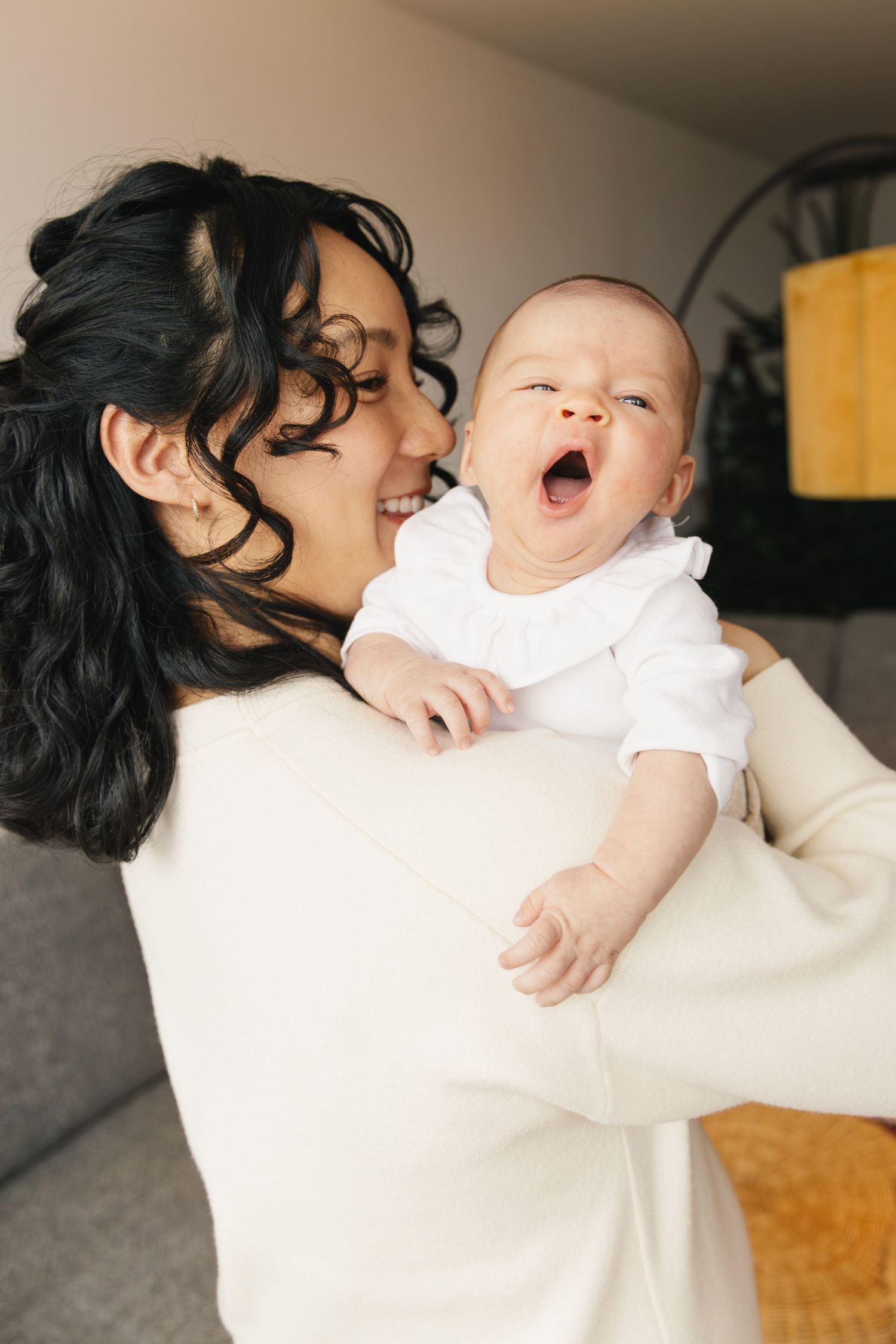 Mother holding her yawning newborn during a lifestyle newborn photoshoot in Switzerland.