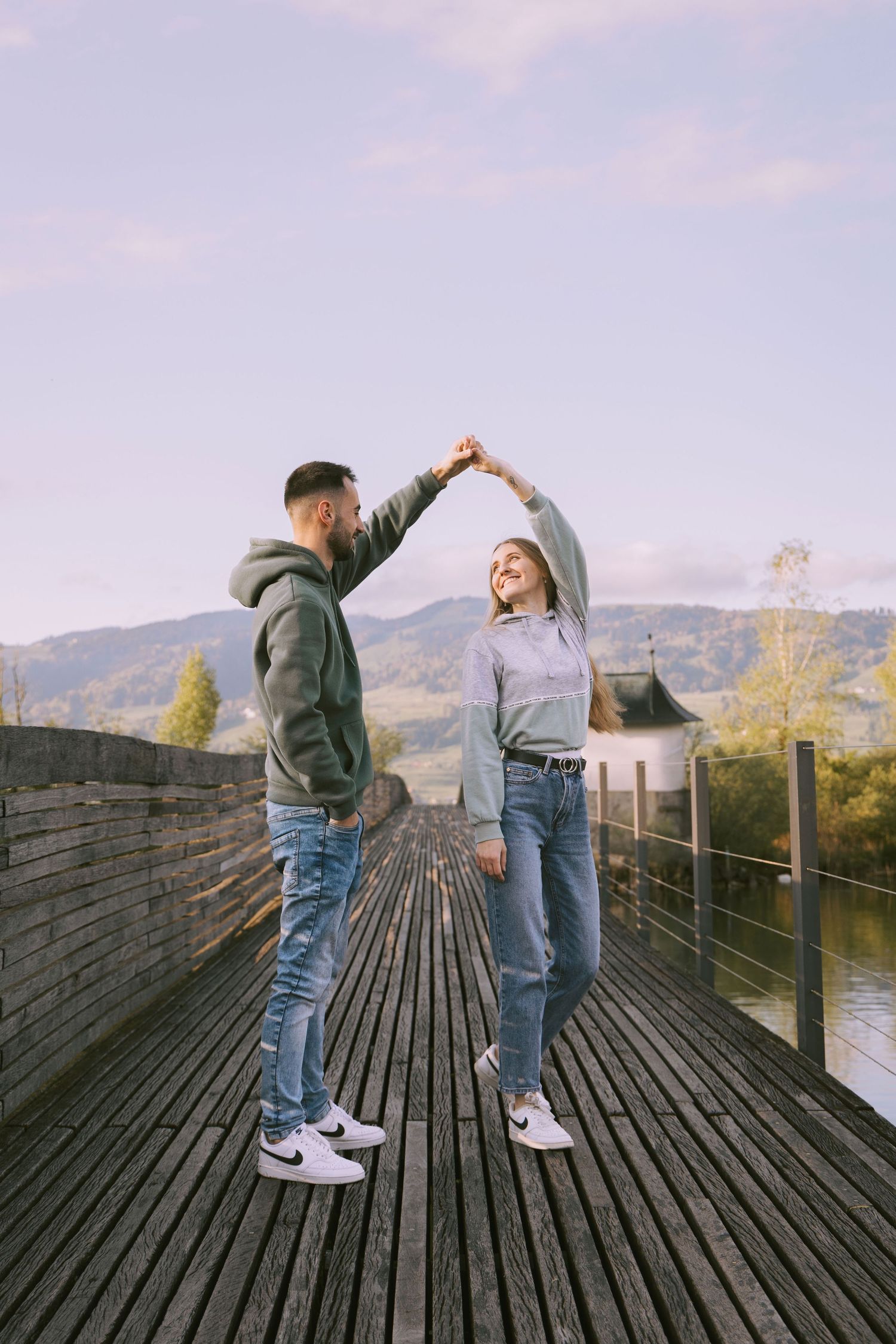 Couple dancing together on a wooden bridge during a romantic photoshoot in Switzerland.