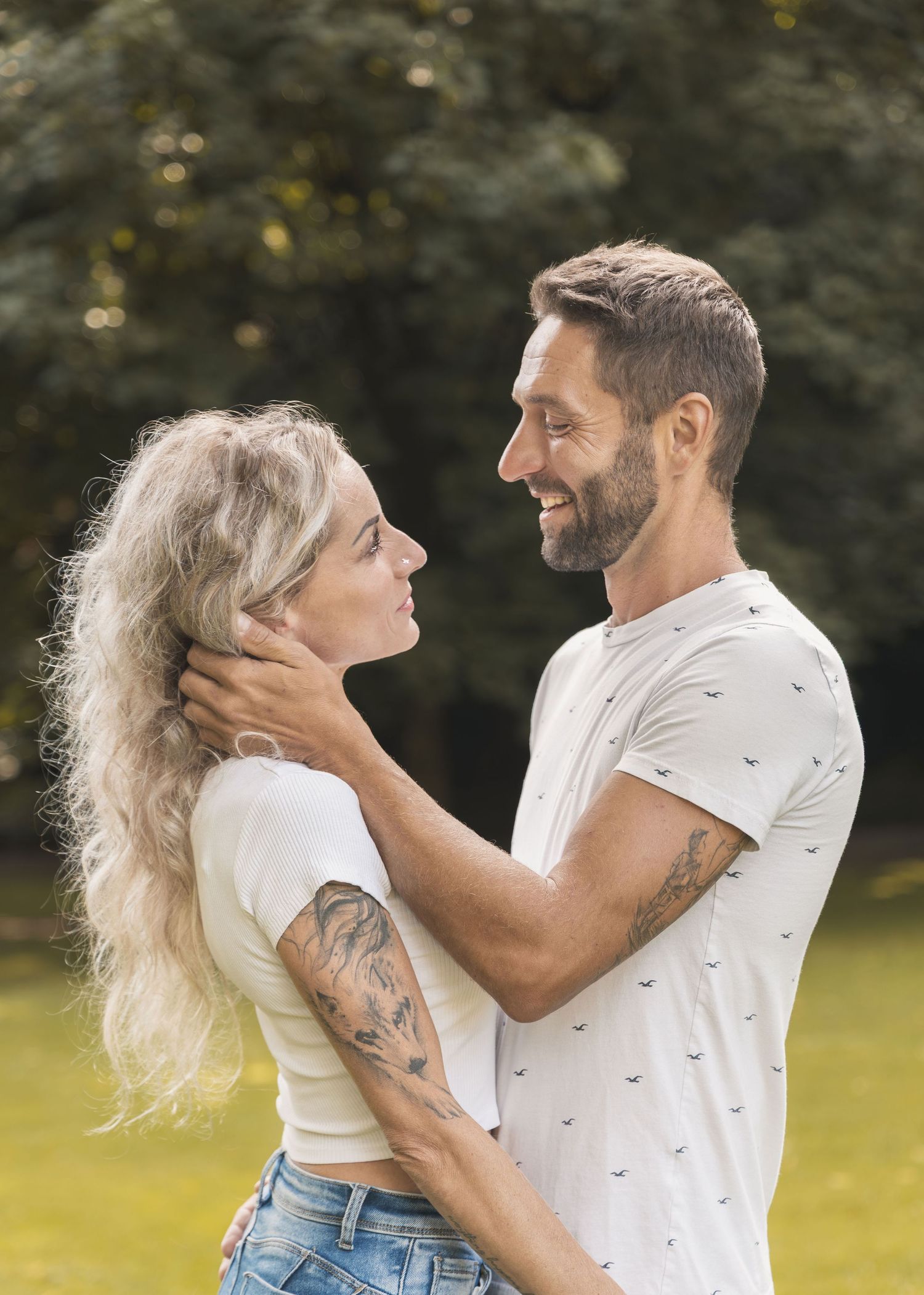 Man gently touching his partner’s face during a summer couples photoshoot in the park.